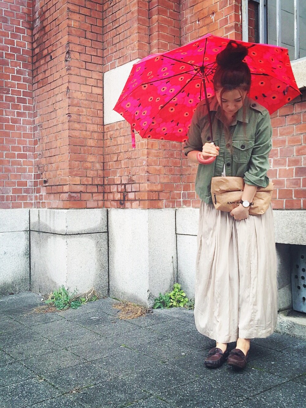 グリーン系のミリタリージャケット、ベージュ系のクラッチバッグ、ベージュ系のスカートを着用したレディースの春コーディネートの1枚目の写真