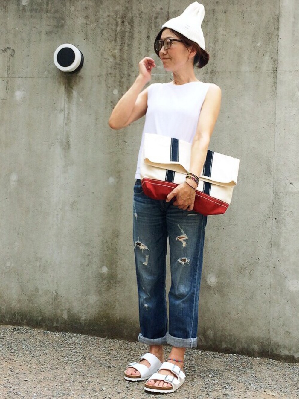 ブラック系のTシャツ/カットソー、ブルー系のデニムパンツ、ブルー系のクラッチバッグを着用したレディースの夏コーディネートの1枚目の写真