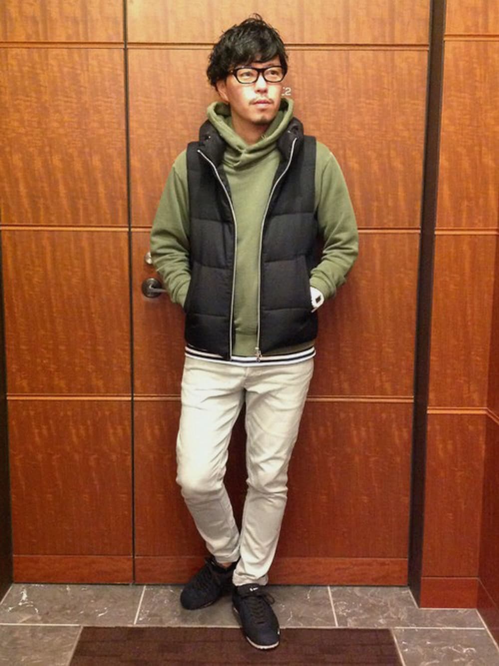 ブラック系のダウンベスト、グリーン系のパーカー、グレー系のその他パンツを着用したメンズの秋コーディネートの1枚目の写真