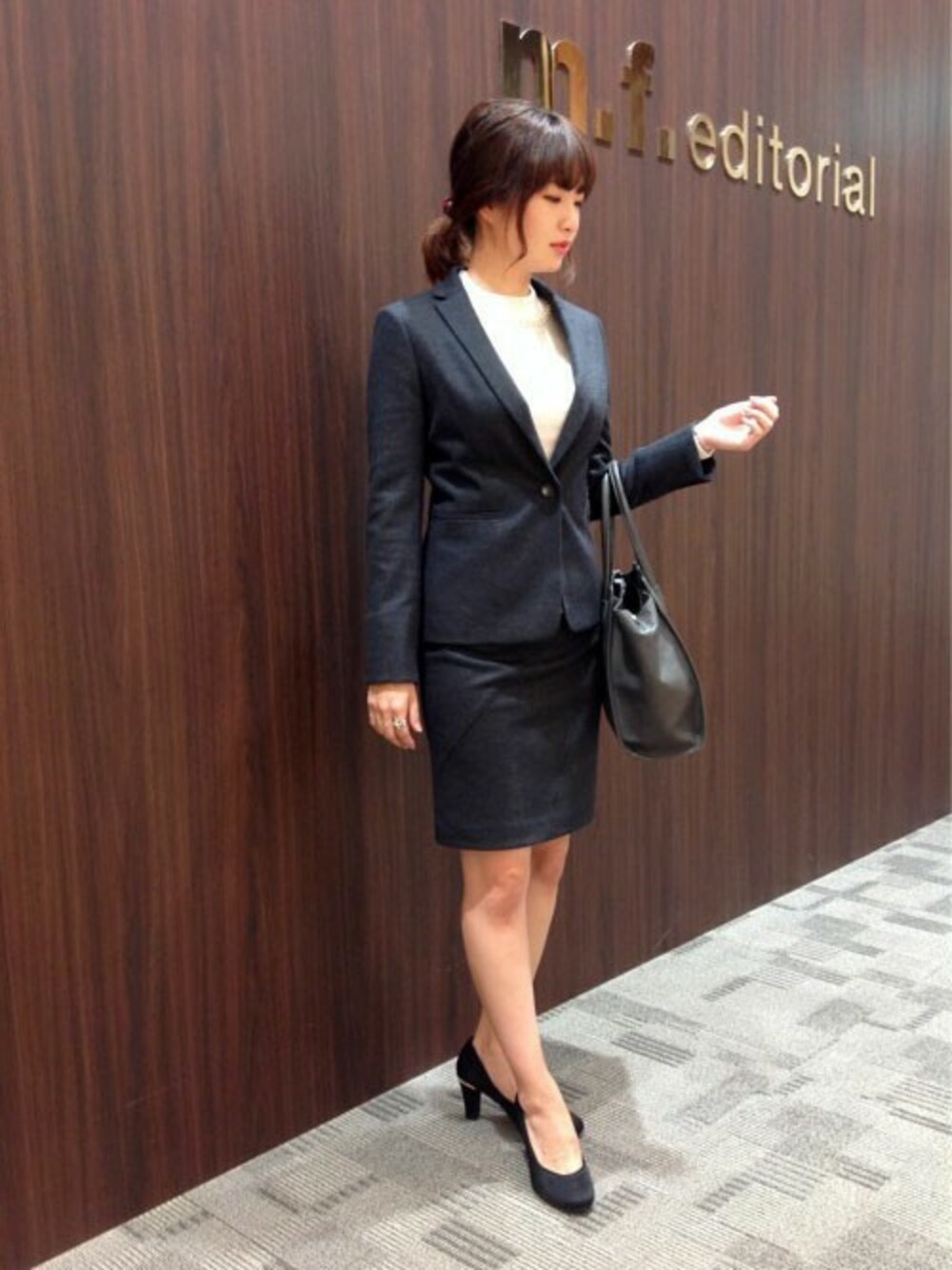 グレー系のスーツジャケット、グレー系のスーツスカート、ホワイト系のニット/セーターを着用したレディースの秋コーディネートの1枚目の写真