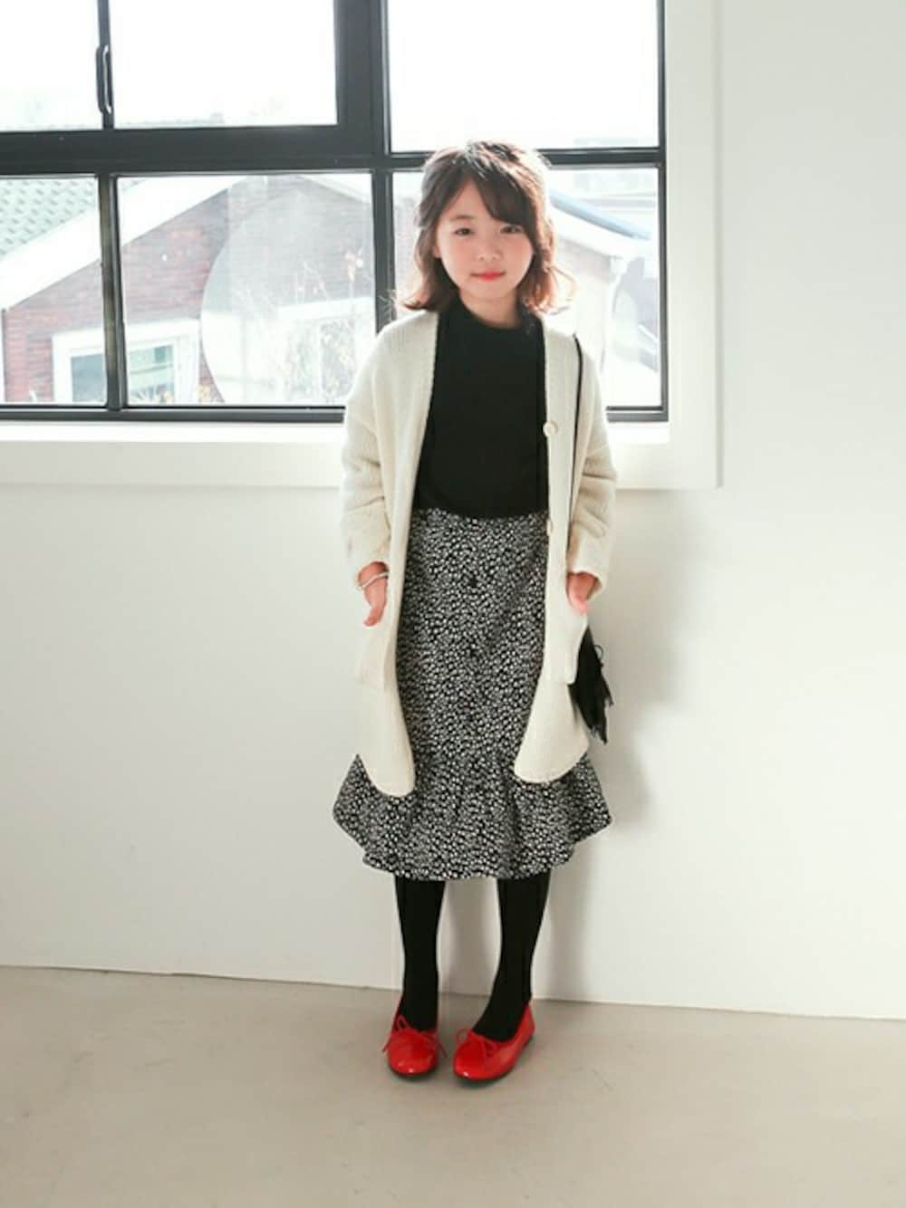 ホワイト系のカーディガン/ボレロ、ブラック系のスカート、ホワイト系のその他トップスを着用したキッズの秋コーディネートの1枚目の写真