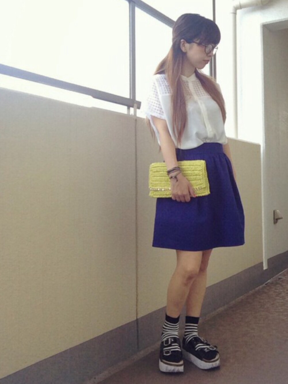 ホワイト系のシャツ/ブラウス、イエロー系のクラッチバッグ、ブルー系のスカートを着用したレディースの夏コーディネートの1枚目の写真