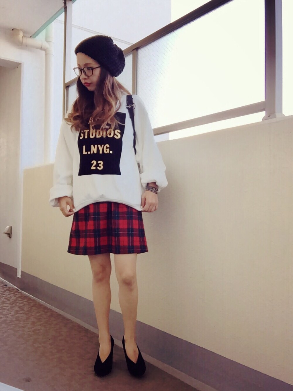 ホワイト系のスウェット、ブラック系のトートバッグ、レッド系のスカートを着用したレディースの秋コーディネートの1枚目の写真