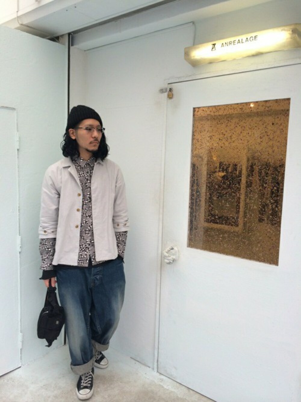 グレー系のステンカラーコート、ブルー系のデニムパンツ、ブラック系のボディバッグ/ウエストポーチを着用したメンズの春コーディネートの1枚目の写真