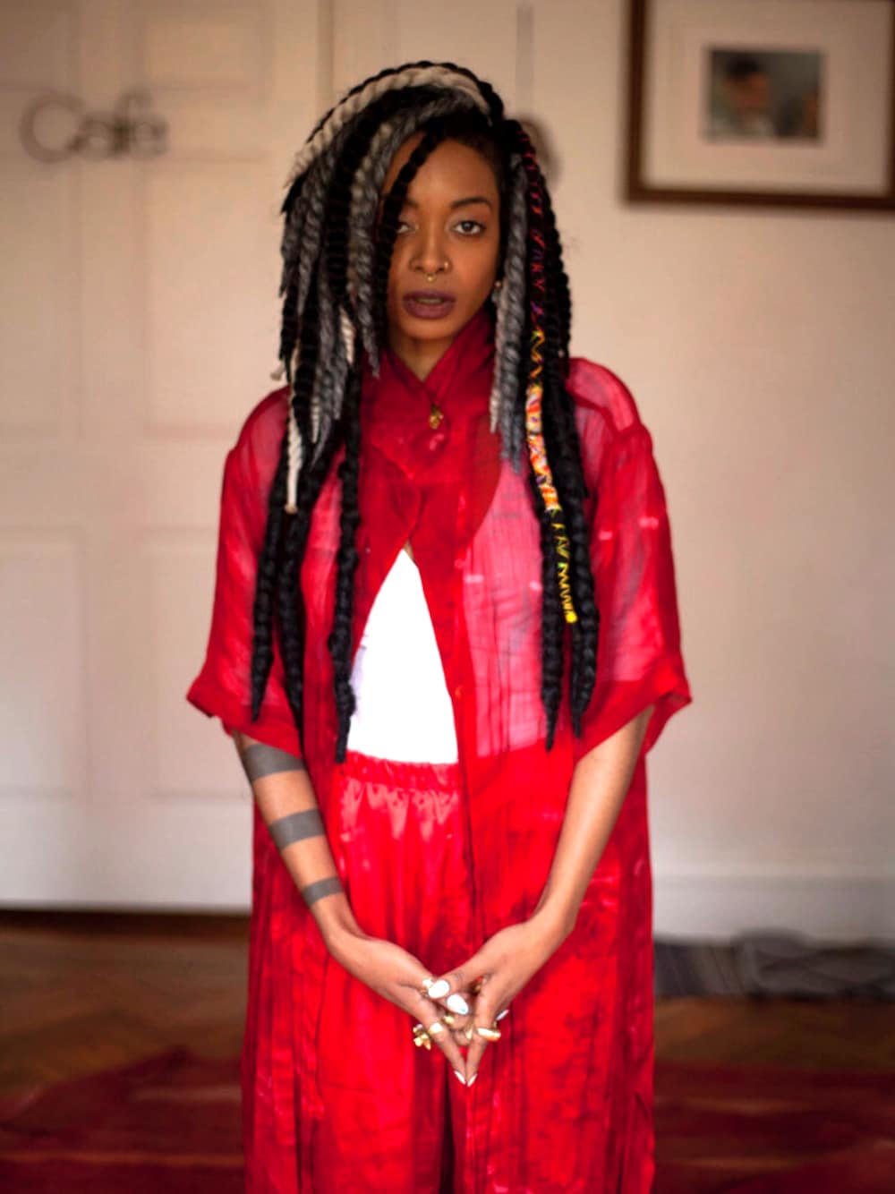 レッド系のチュニック、レッド系のスラックス、ホワイト系のキャミソールを着用したレディースの秋コーディネートの1枚目の写真