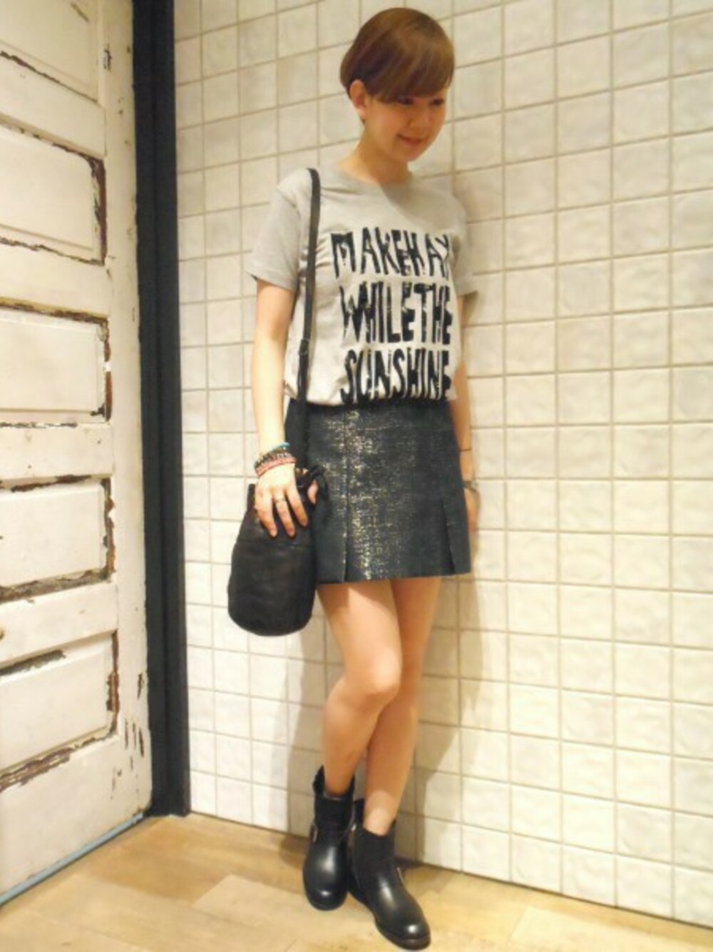 グレー系のTシャツ/カットソー、ゴールド系のスカート、ブラック系のブーツを着用したレディースの夏コーディネートの1枚目の写真