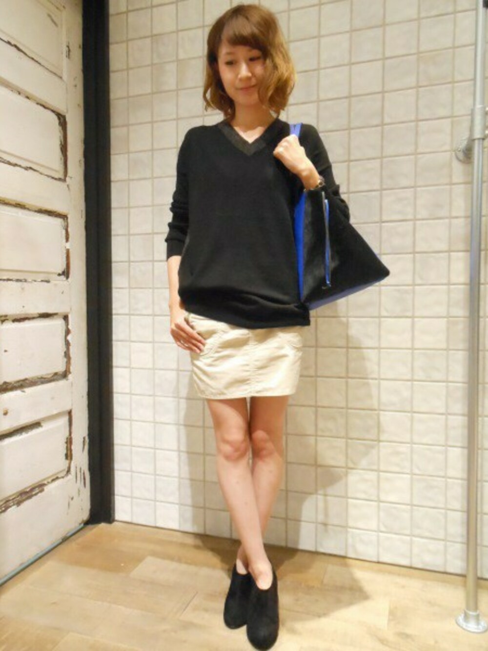 ブラック系のニット/セーター、ホワイト系のスカート、ブラック系のブーティを着用したレディースの秋コーディネートの1枚目の写真