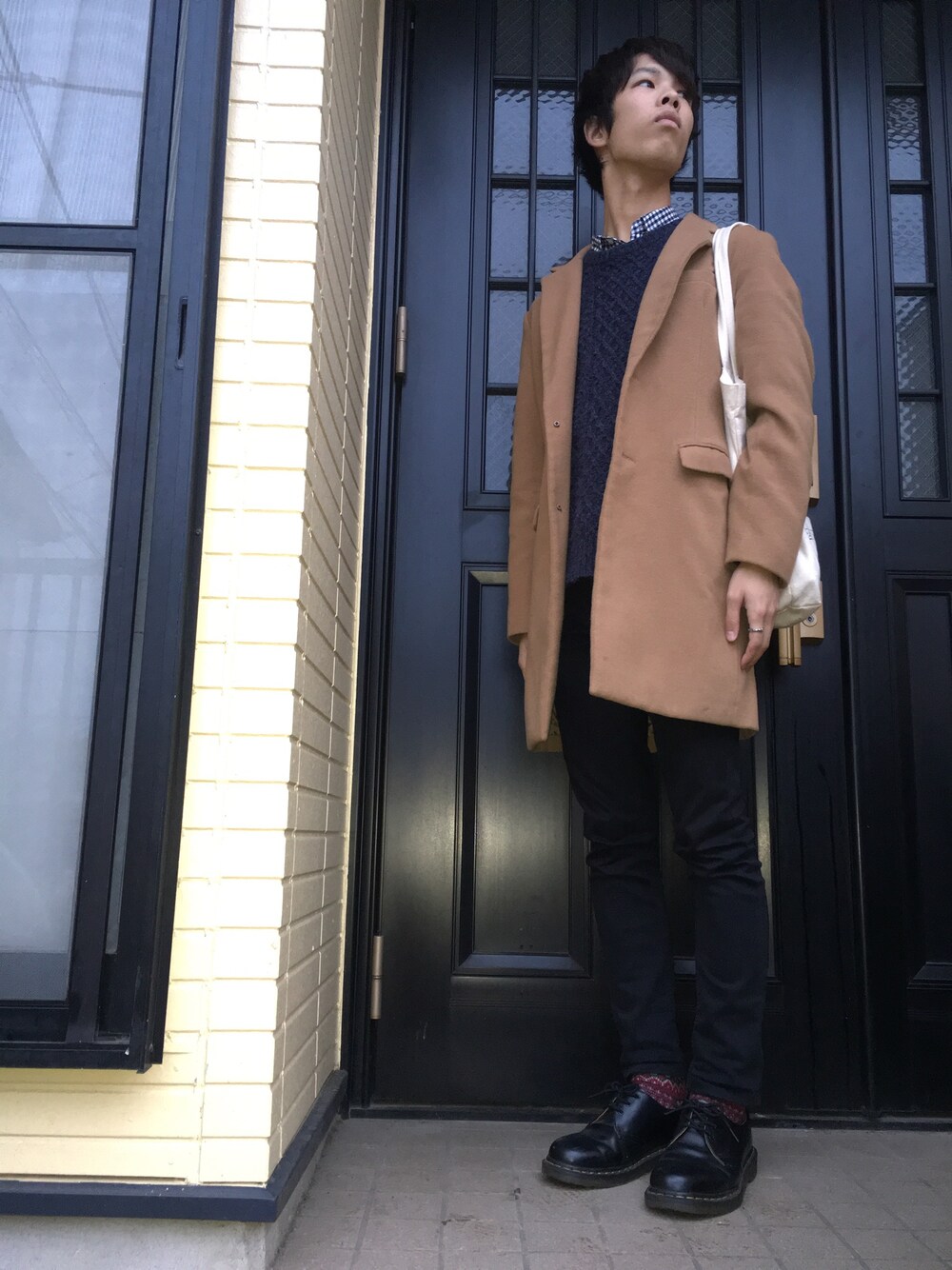 イエロー系のステンカラーコート、ブルー系のニット/セーター、ブラック系のシャツ/ブラウスを着用したメンズの冬コーディネートの1枚目の写真