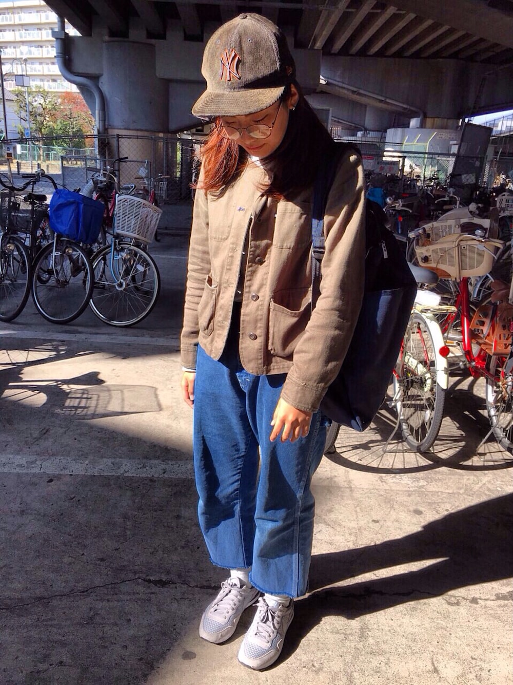 ブルー系のバックパック/リュック、ブルー系のデニムパンツ、グレー系のスニーカーを着用したレディースの秋コーディネートの1枚目の写真