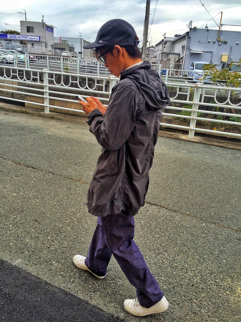 グレー系のステンカラーコート、ブルー系のデニムパンツ、ホワイト系のスニーカーを着用したメンズの秋コーディネートの1枚目の写真