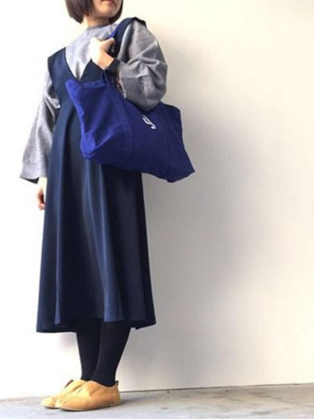 グレー系のニット/セーター、ベージュ系のジャンパースカートを着用したレディースの秋コーディネートの1枚目の写真