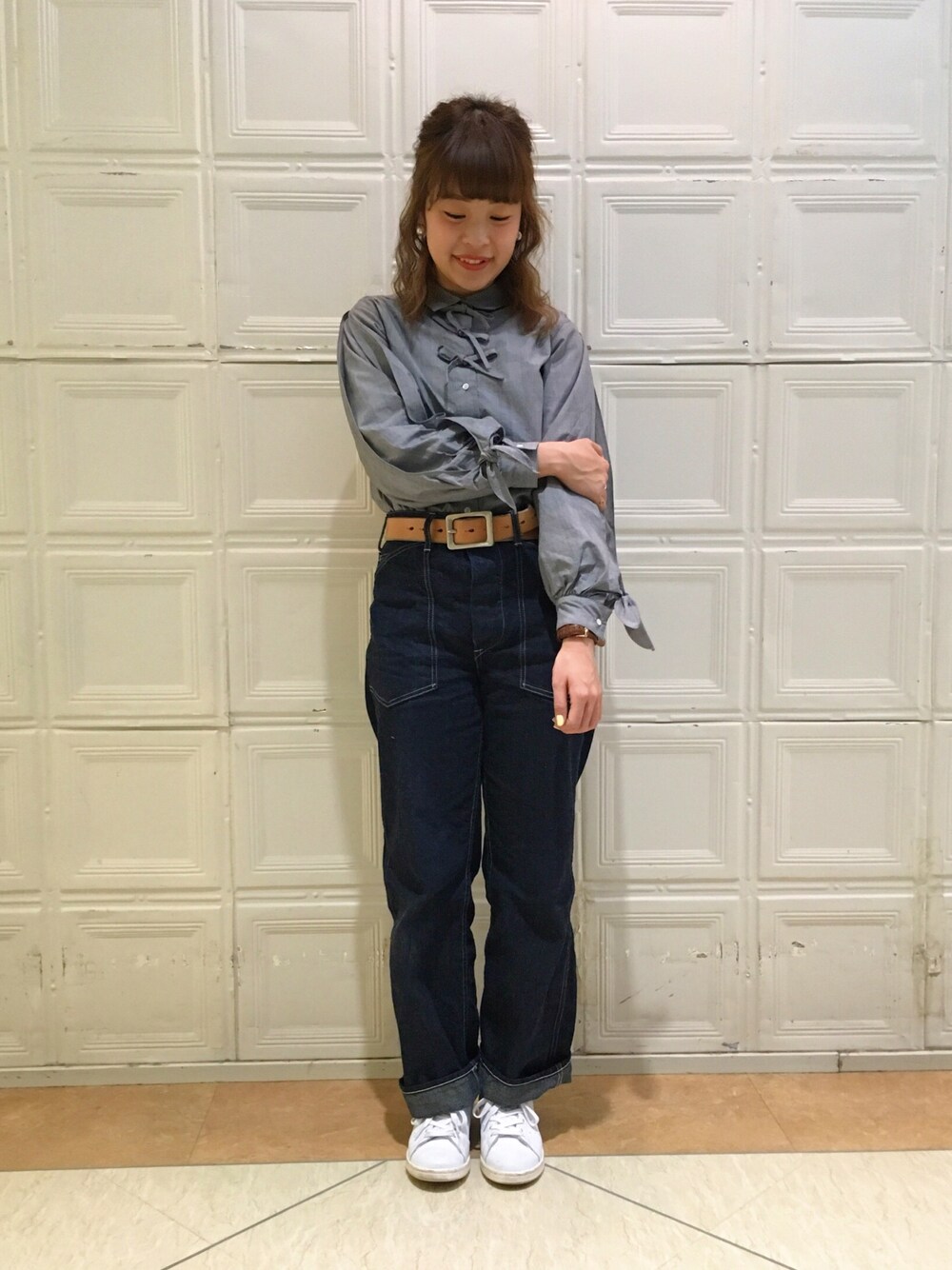 グレー系のシャツ/ブラウス、ブルー系のデニムパンツ、ホワイト系のスニーカーを着用したレディースの冬コーディネートの1枚目の写真