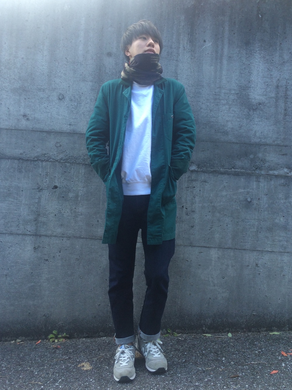 グリーン系のステンカラーコート、ホワイト系のスウェット、ブルー系のデニムパンツを着用したメンズの冬コーディネートの1枚目の写真