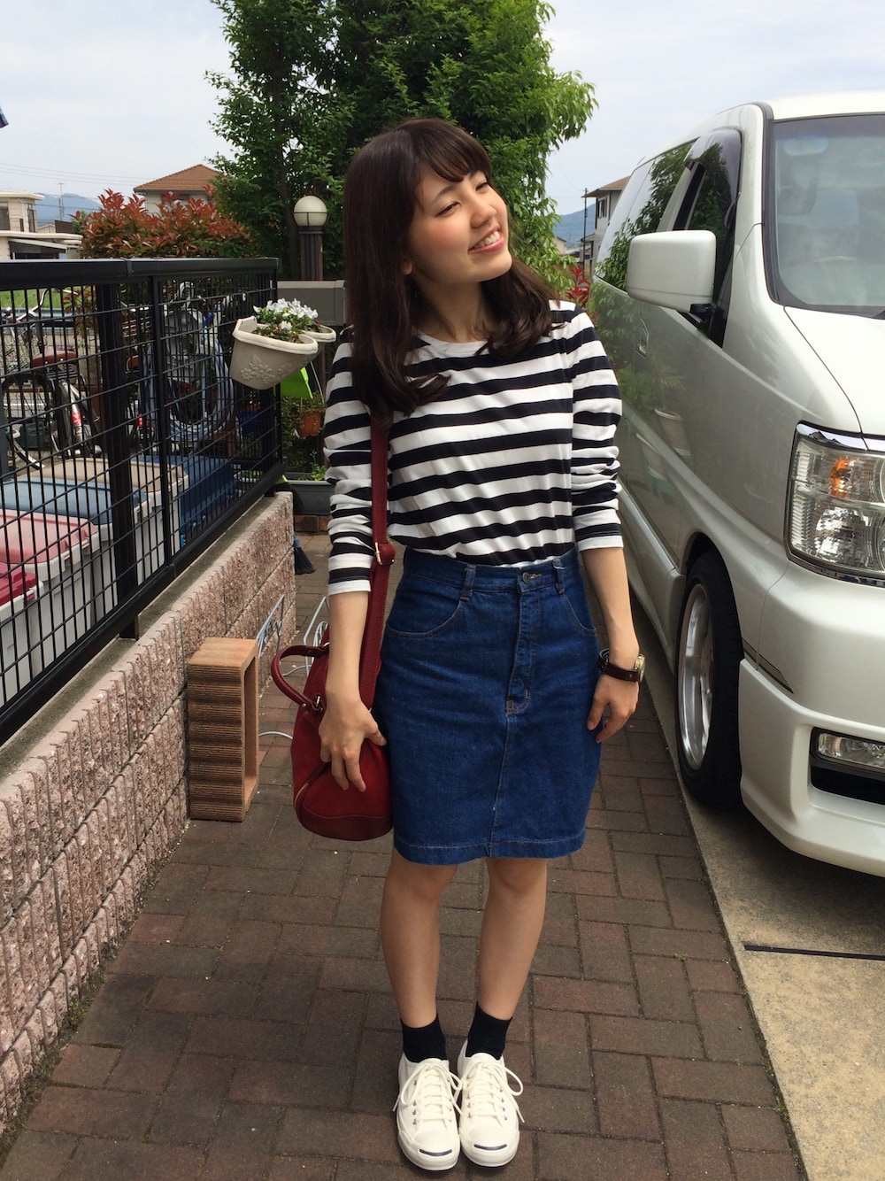 ブラック系のTシャツ/カットソー、ホワイト系のスニーカー、ブルー系のデニムスカートを着用したレディースの春コーディネートの1枚目の写真