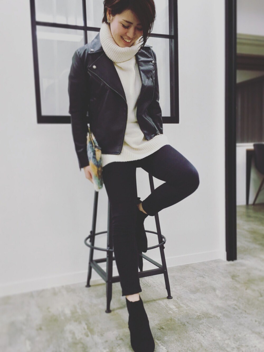 グリーン系のクラッチバッグ、ブラック系のデニムパンツ、シルバー系のピアス（両耳用）を着用したレディースの秋コーディネートの1枚目の写真