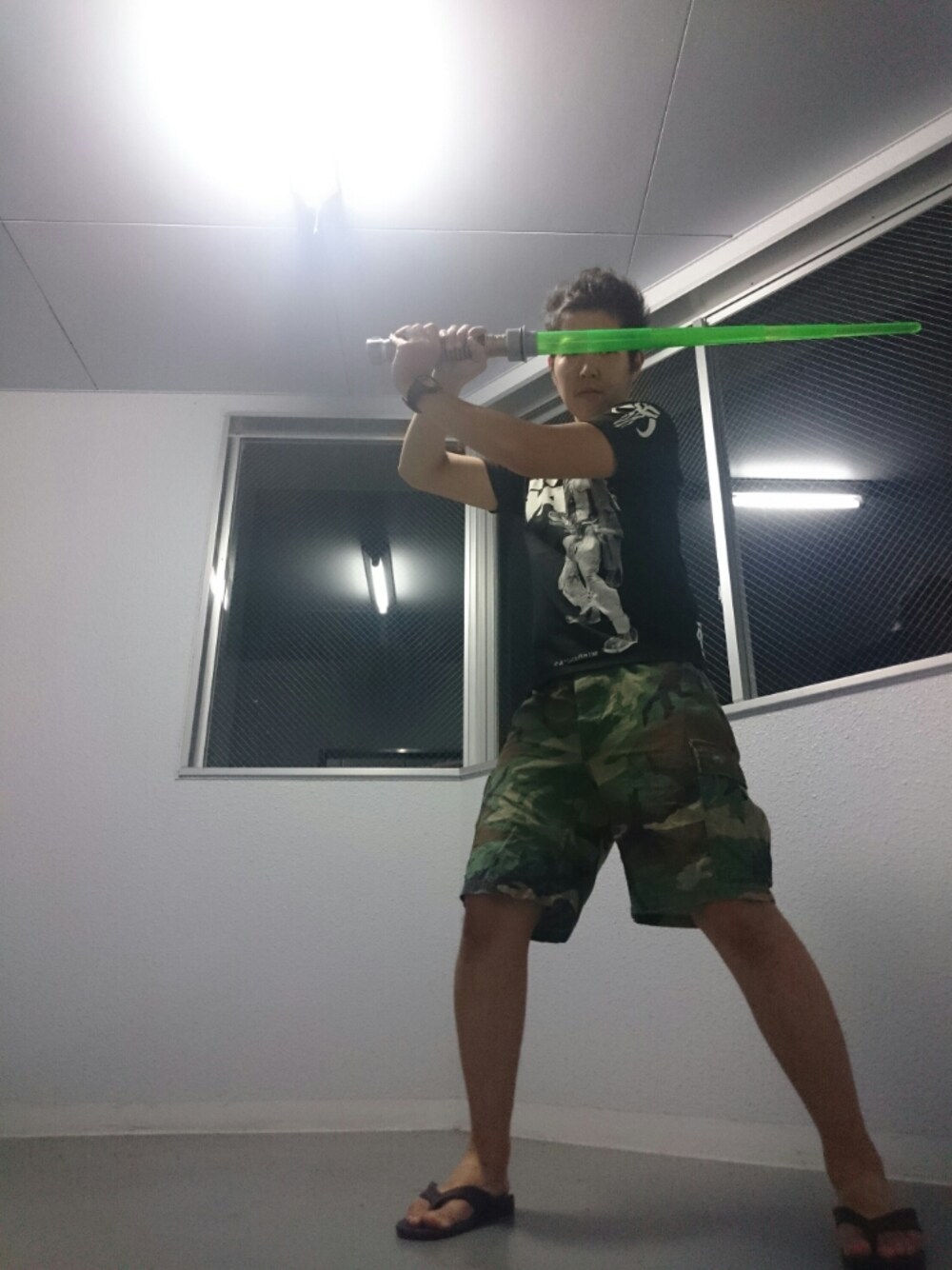 グリーン系のパンツ、ブラック系のTシャツ/カットソー、ブラック系のサンダルを着用したメンズの夏コーディネートの1枚目の写真