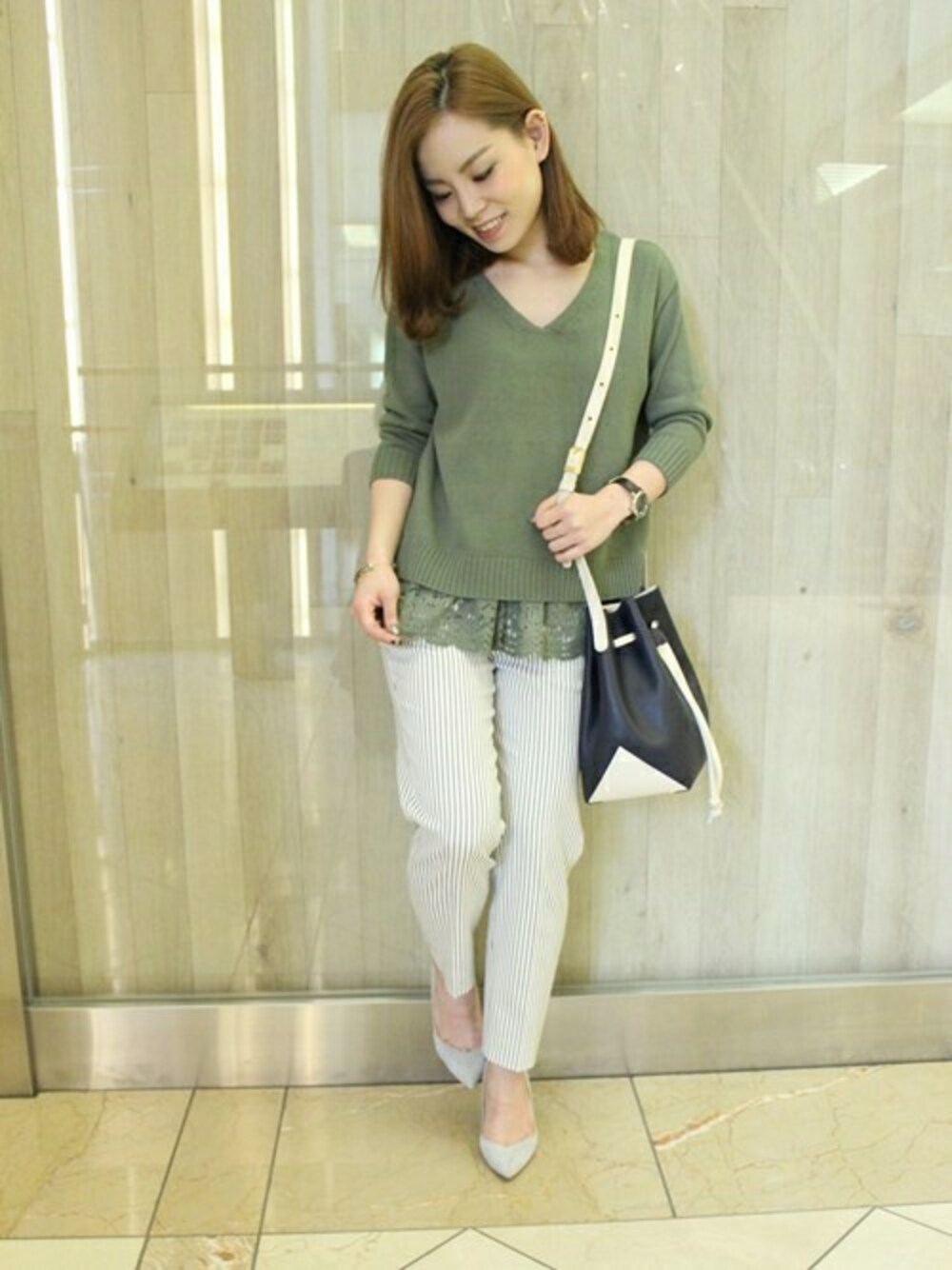 グリーン系のニット/セーター、ホワイト系のその他パンツ、ブルー系のショルダーバッグを着用したレディースの春コーディネートの1枚目の写真
