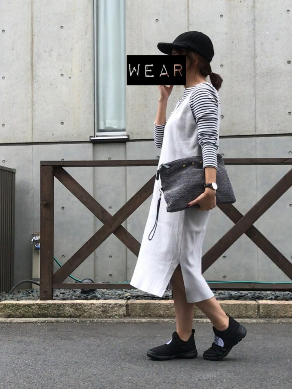 グレー系のクラッチバッグ、ブラック系のシューズ、ブラック系のキャップを着用したレディースの秋コーディネートの1枚目の写真