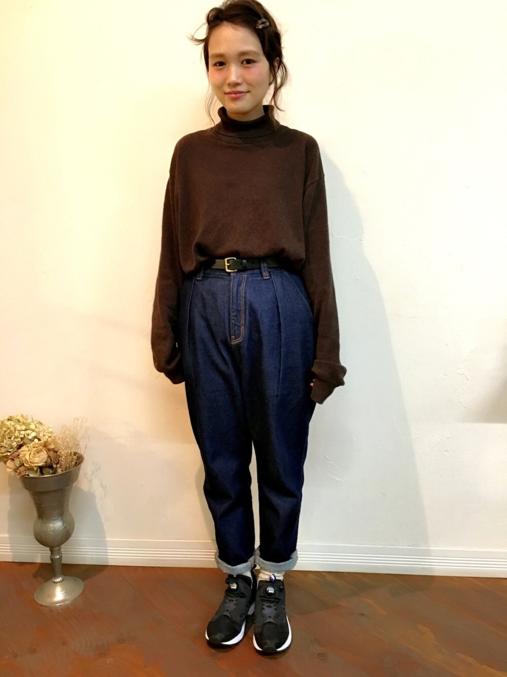 ブルー系のデニムパンツ、ブラック系のスニーカー、ブラウン系のニット/セーターを着用したレディースの冬コーディネートの1枚目の写真