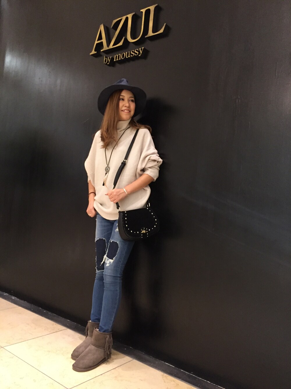 ブルー系のデニムパンツ、ブラック系のショルダーバッグ、ベージュ系のブーツを着用したレディースの秋コーディネートの1枚目の写真