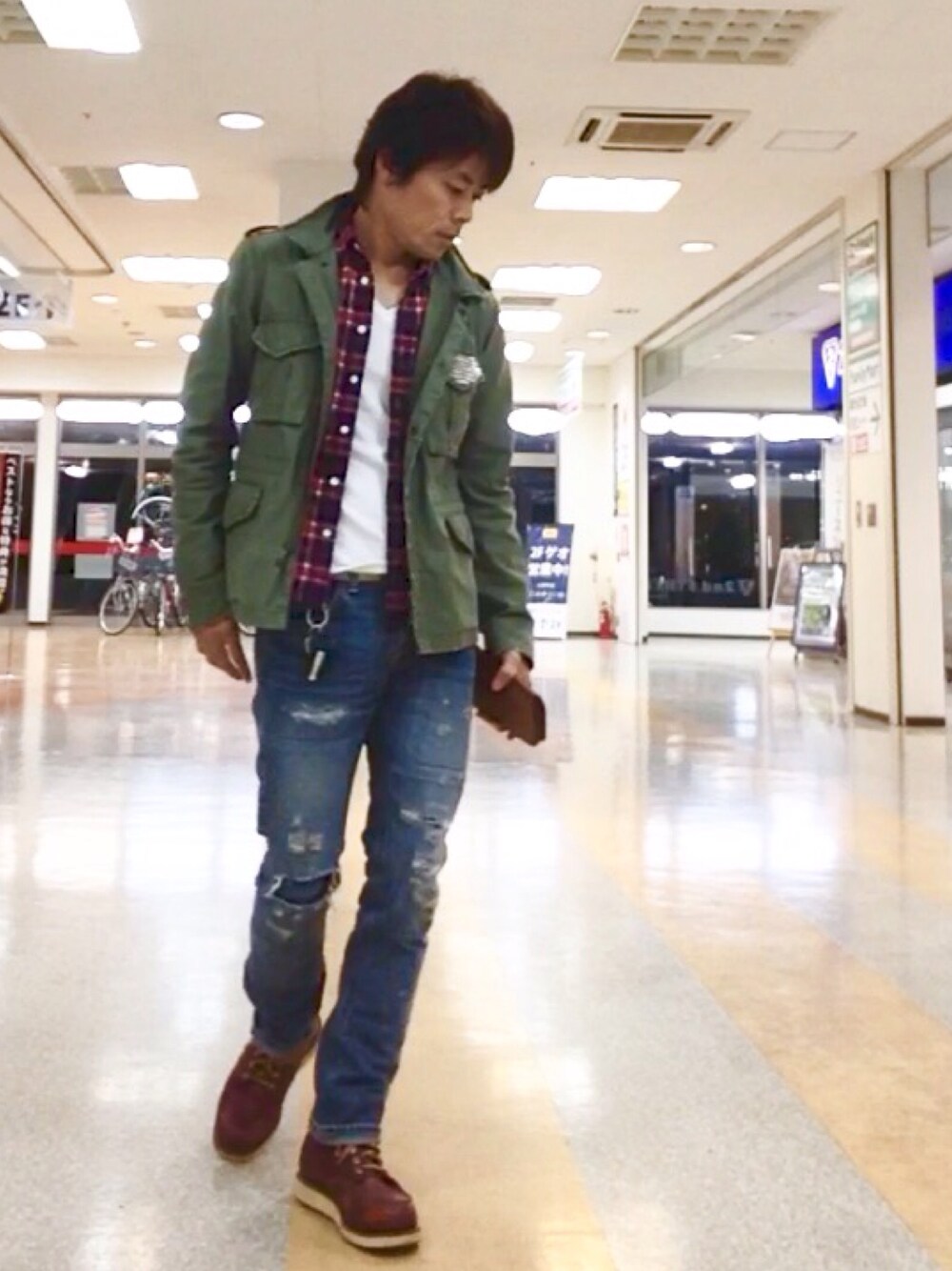 グリーン系のミリタリージャケット、レッド系のシャツ/ブラウス、ブルー系のデニムパンツを着用したメンズの冬コーディネートの1枚目の写真