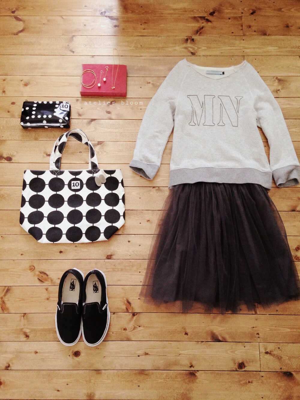 グレー系のスカート、ブラック系のスニーカー、ゴールド系のネックレスを着用したレディースの春コーディネートの1枚目の写真