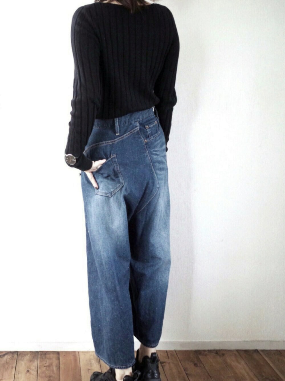 ブラック系のニット/セーター、ブルー系のデニムパンツ、ブラック系のスニーカーを着用したレディースの秋コーディネートの1枚目の写真