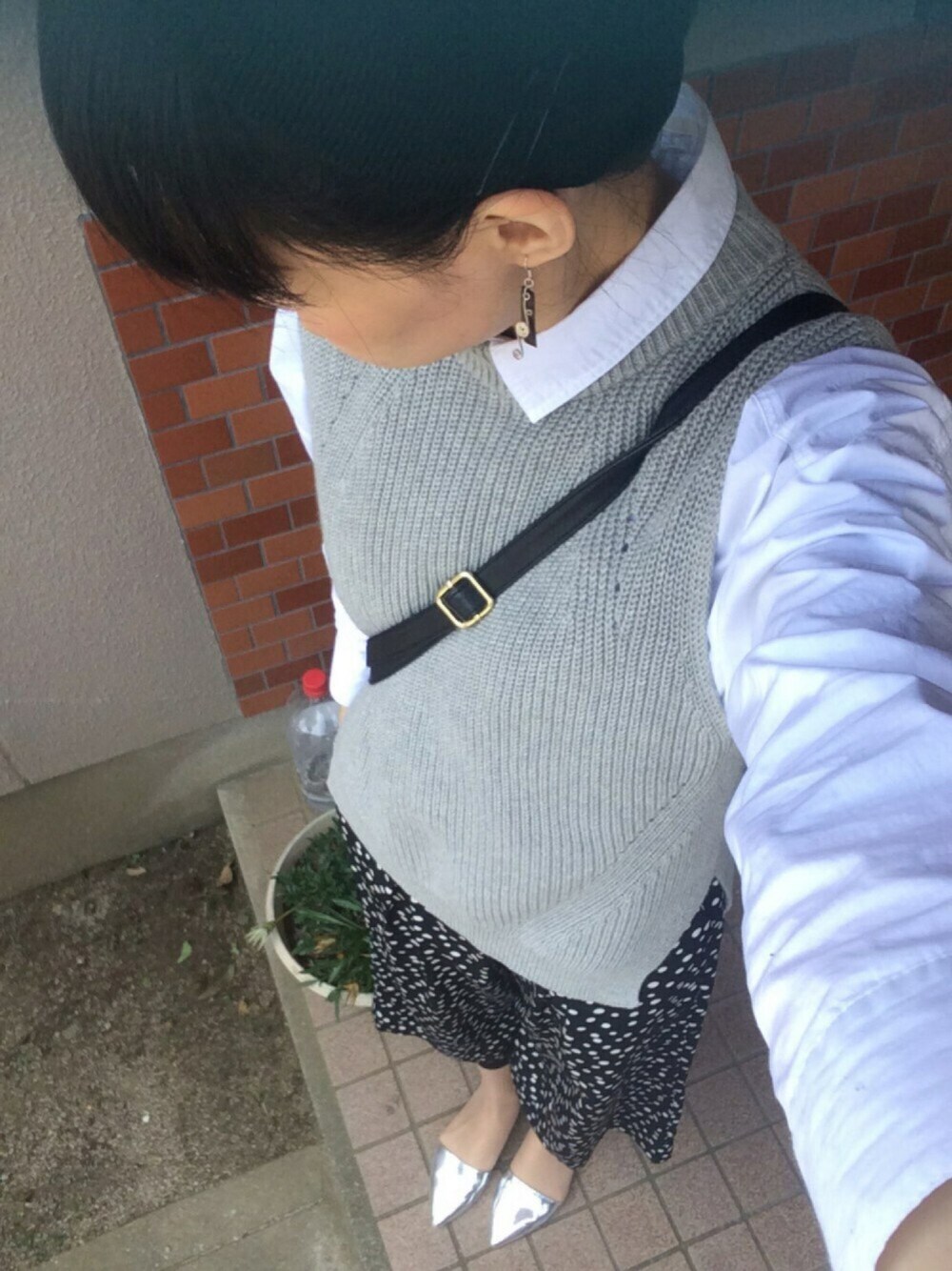 グレー系のベスト、シルバー系のパンプス、ホワイト系のシャツ/ブラウスを着用したレディースの春コーディネートの1枚目の写真