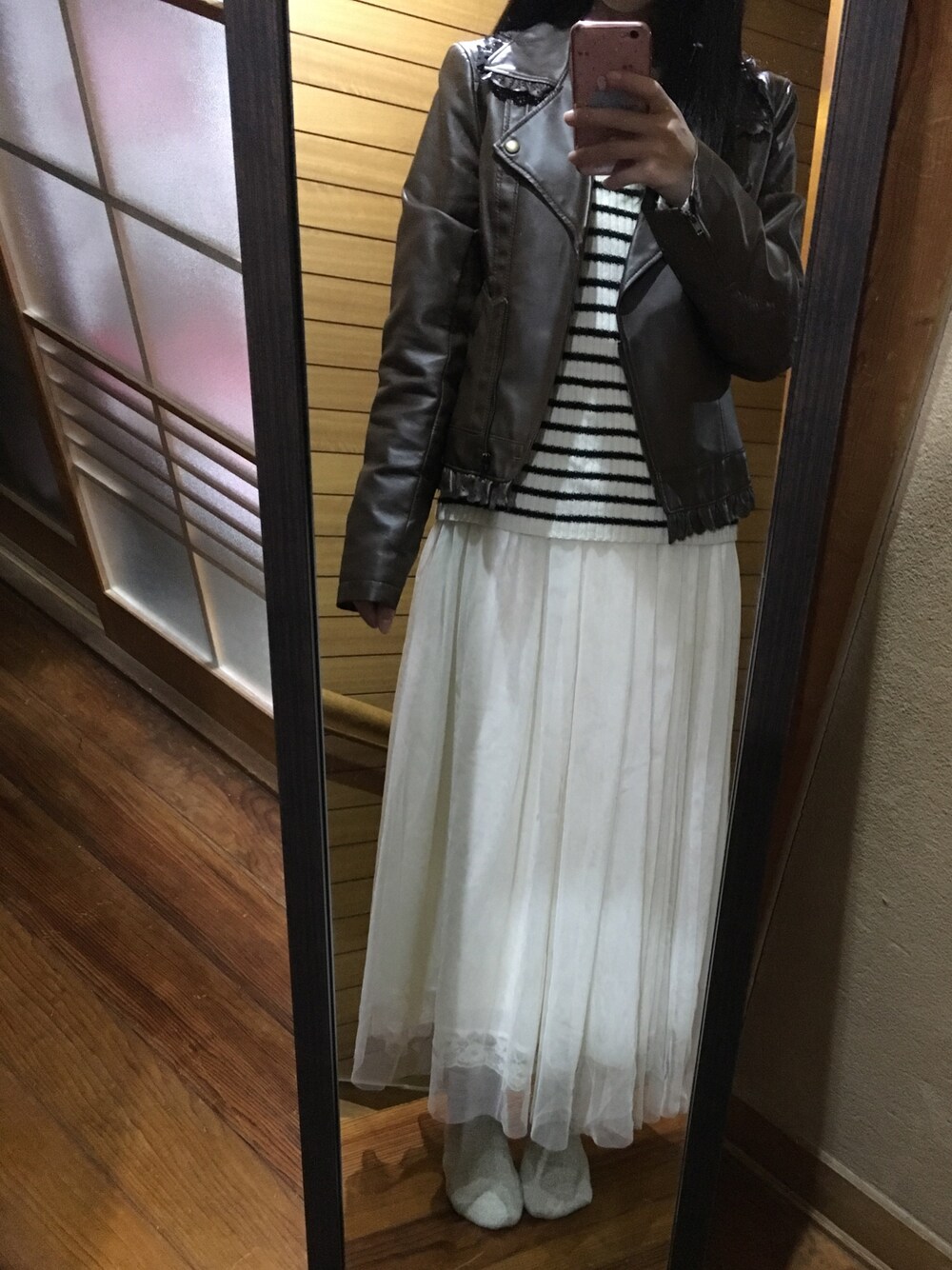 ブラウン系のライダースジャケット、ホワイト系のニット/セーター、ホワイト系のスカートを着用したレディースの秋コーディネートの1枚目の写真