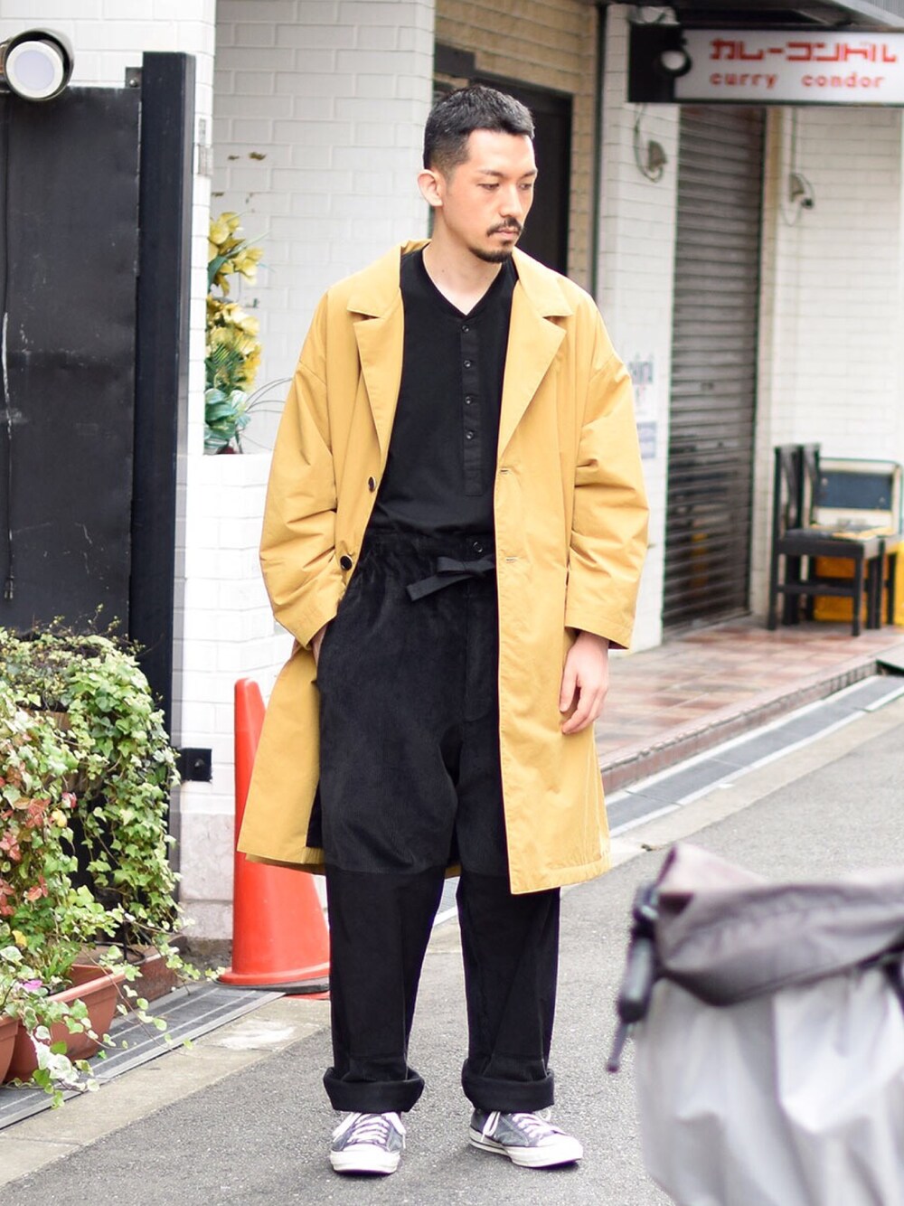イエロー系のステンカラーコート、ブラック系のその他パンツ、ブラック系のTシャツ/カットソーを着用したメンズの秋コーディネートの1枚目の写真