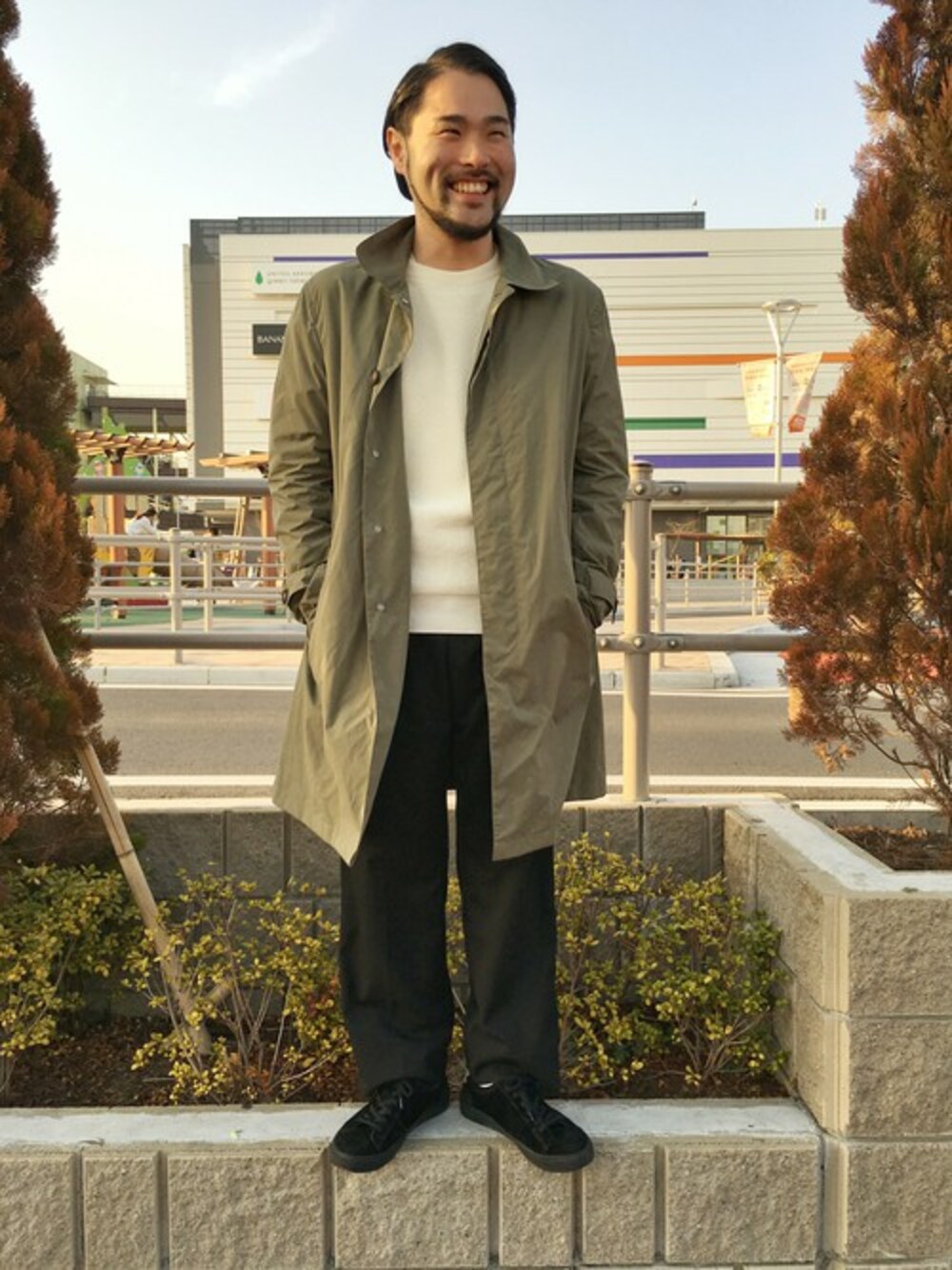 「スニーカー、ブラック、トレンチコート、ステンカラーコート、ワイドパンツ、白ニット、春、スプリングコート、シンプルコーデ、オトナカジュアル」｜「MORGAN HOMMEのパッカブルステンカラーコート（ステンカラーコート、グリーン系）」を使った、PAPASOLTさん（メンズ・171cm）の春コーディネートの1枚目の写真