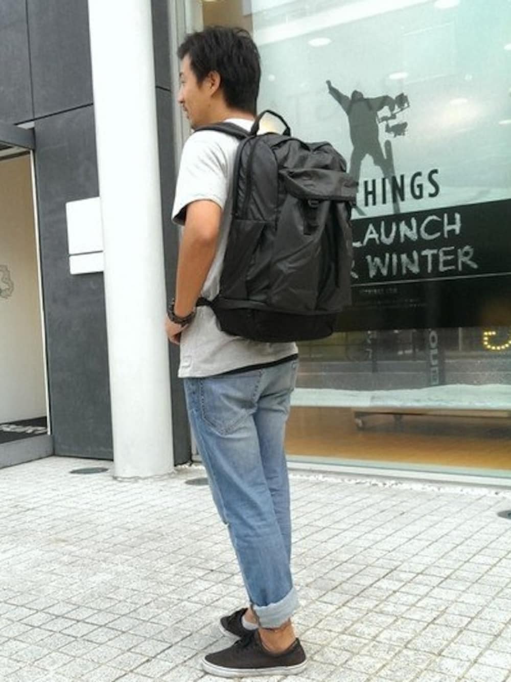 ブラック系のバックパック/リュック、グレー系のTシャツ/カットソー、ブラック系のスニーカーを着用したメンズの秋コーディネートの1枚目の写真