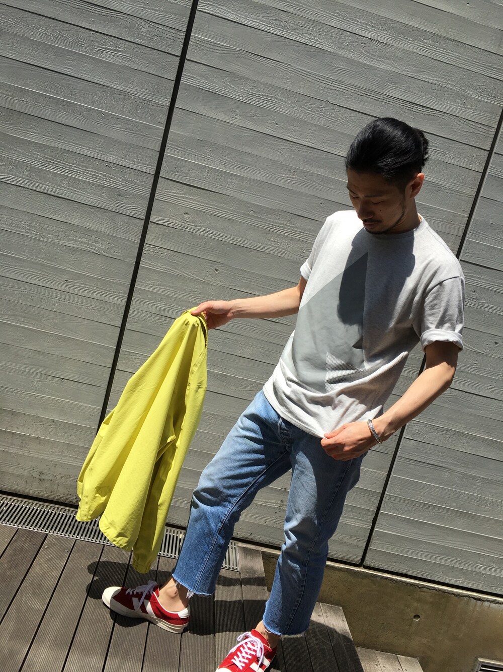 イエロー系のナイロンジャケット、グレー系のTシャツ/カットソーを着用したメンズの春コーディネートの1枚目の写真