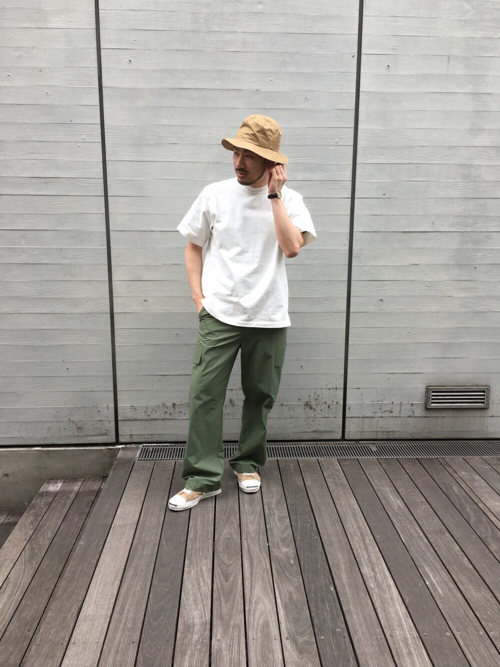 ホワイト系のTシャツ/カットソー、ベージュ系のスニーカー、グリーン系のカーゴパンツを着用したメンズの春コーディネートの1枚目の写真