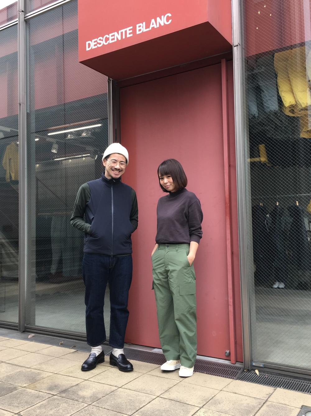 ブルー系のベスト、グリーン系のニット/セーター、ブラック系のドレスシューズを着用したメンズの秋コーディネートの1枚目の写真
