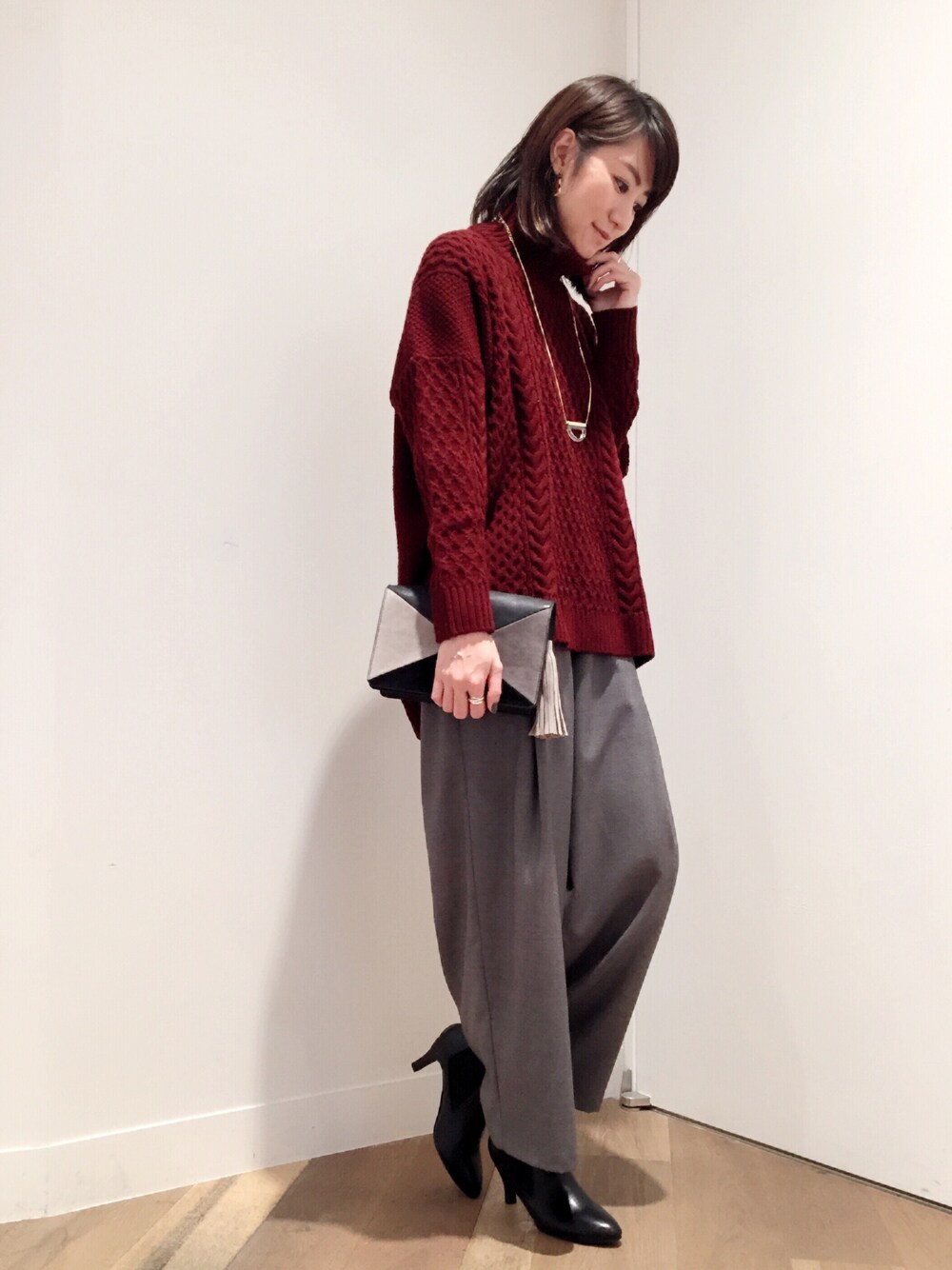 グレー系のその他パンツ、ブラック系のブーティ、レッド系のニット/セーターを着用したレディースの冬コーディネートの1枚目の写真