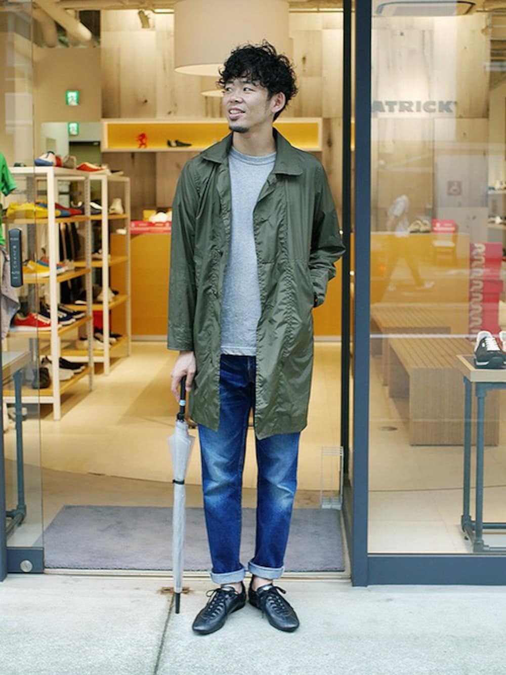 ブラック系のスニーカー、グリーン系のステンカラーコート、グレー系のTシャツ/カットソーを着用したメンズの夏コーディネートの1枚目の写真