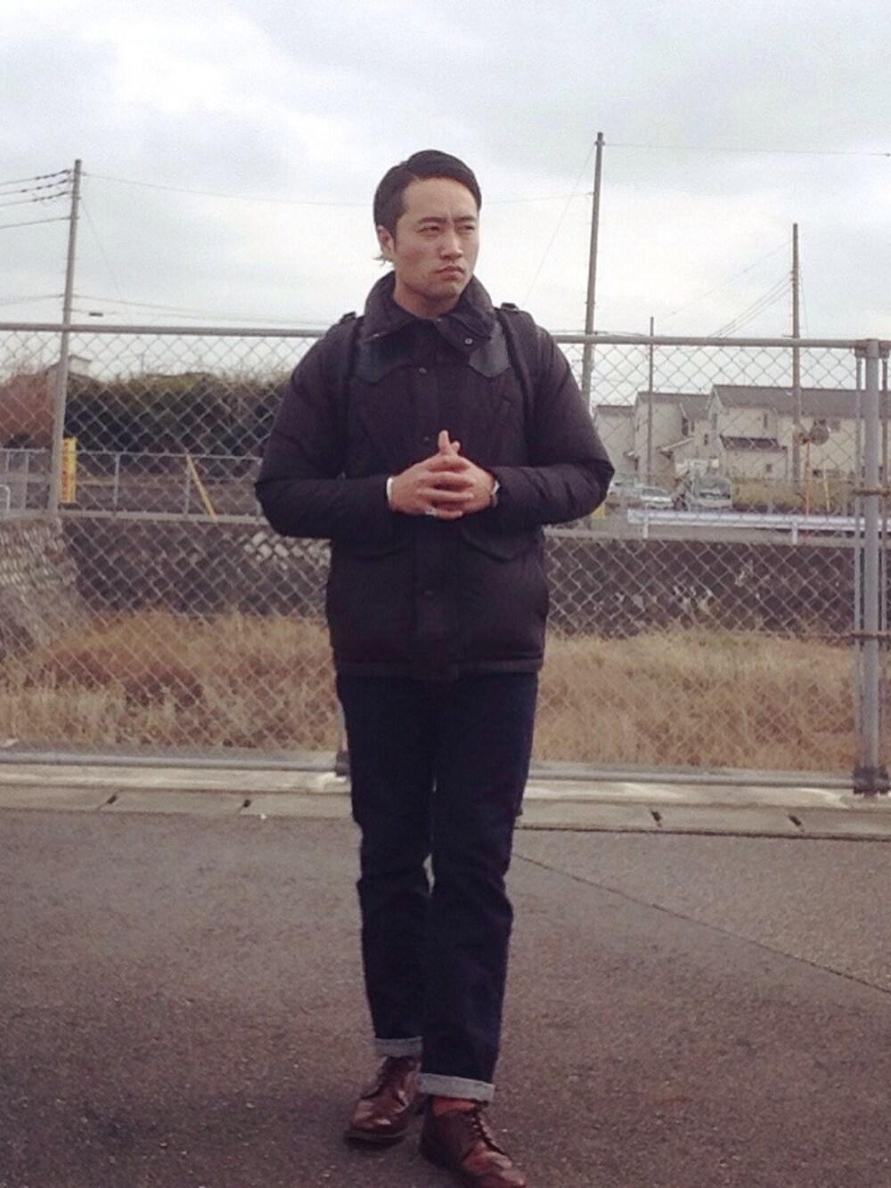 ブルー系のデニムパンツ、ブラック系のダウンジャケット/コート、ブラウン系のドレスシューズを着用したメンズの冬コーディネートの1枚目の写真