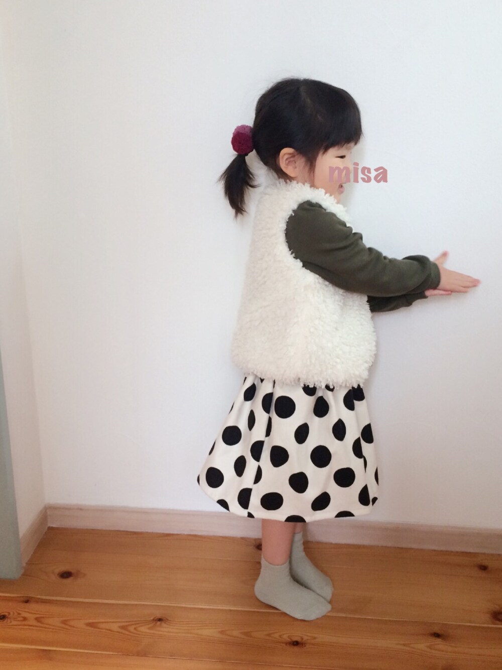 グリーン系のスウェット、ホワイト系のベスト、ホワイト系のスカートを着用したキッズの冬コーディネートの1枚目の写真