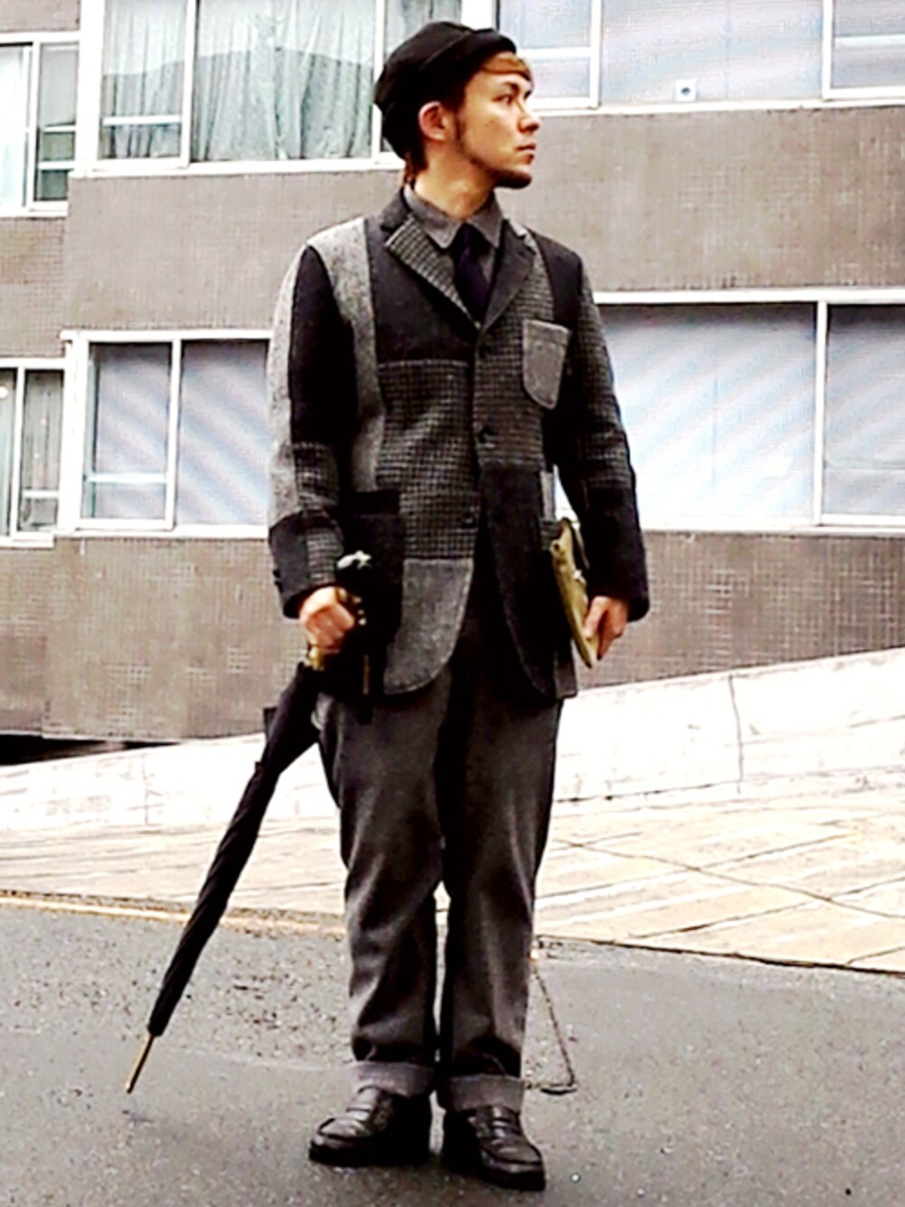 グレー系のテーラードジャケット、ブラック系のつなぎ/オールインワン、グリーン系のクラッチバッグを着用したメンズの冬コーディネートの1枚目の写真