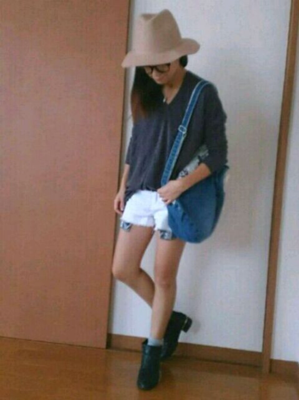 グレー系のチュニック、ブルー系のバックパック/リュック、ホワイト系のデニムパンツを着用したレディースの秋コーディネートの1枚目の写真