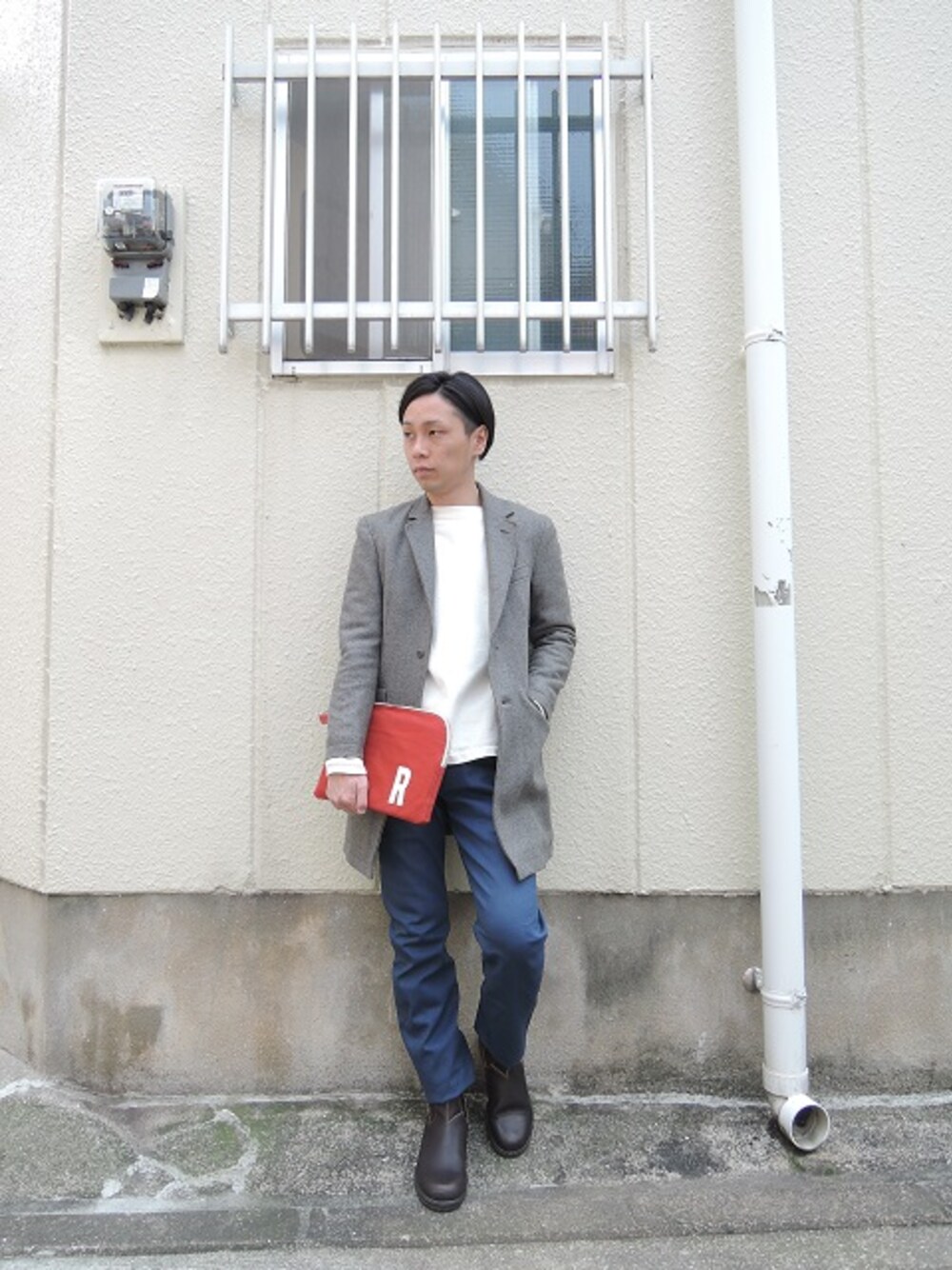 グレー系のチェスターコート、ホワイト系のTシャツ/カットソー、ブルー系のチノパンツを着用したメンズの冬コーディネートの1枚目の写真