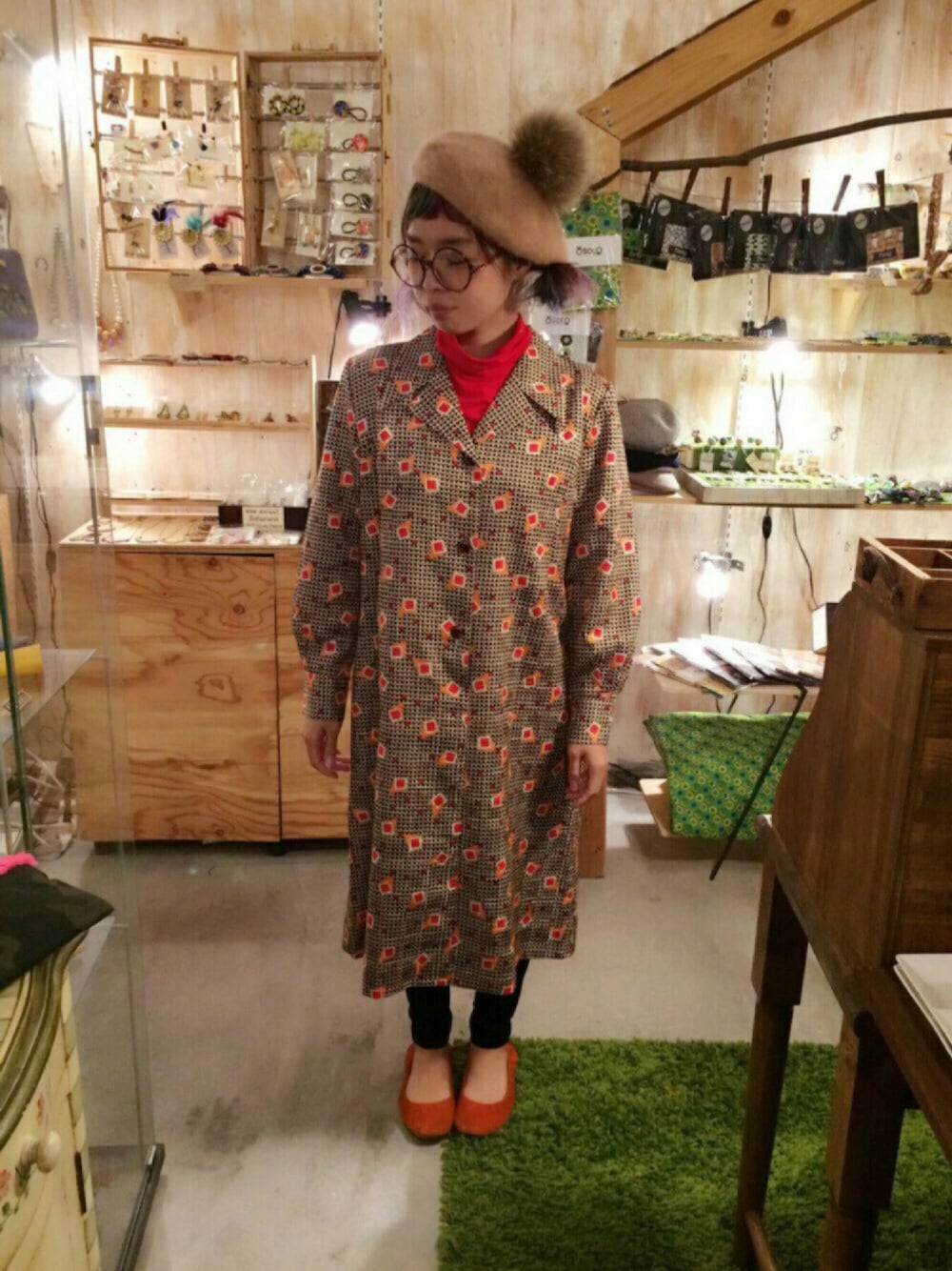 ベージュ系のワンピース、オレンジ系のバレエシューズ、ブラウン系のアクセサリーを着用したレディースの冬コーディネートの1枚目の写真