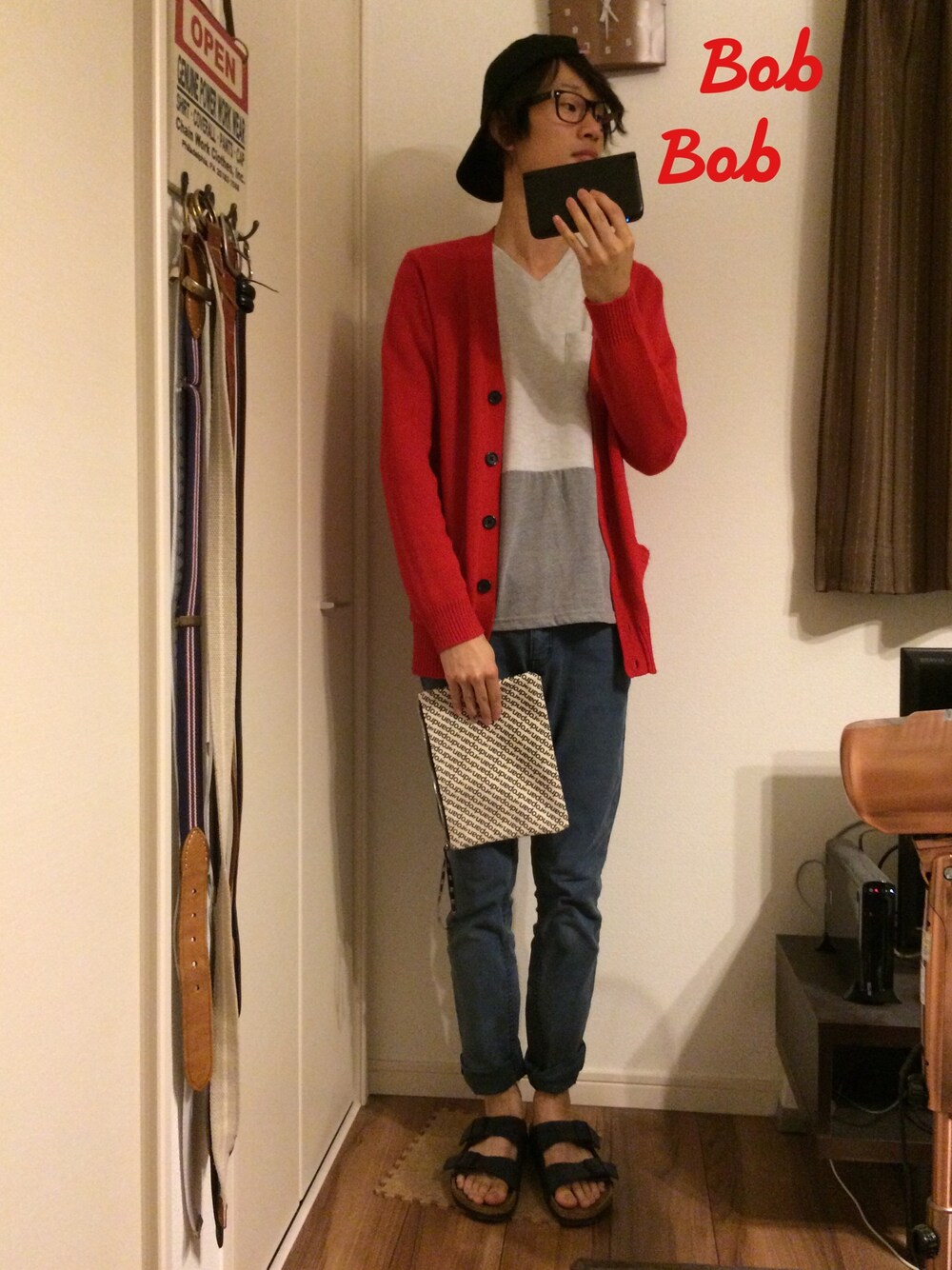 レッド系のカーディガン/ボレロ、ブラック系のサンダル、ブルー系のデニムパンツを着用したメンズの秋コーディネートの1枚目の写真