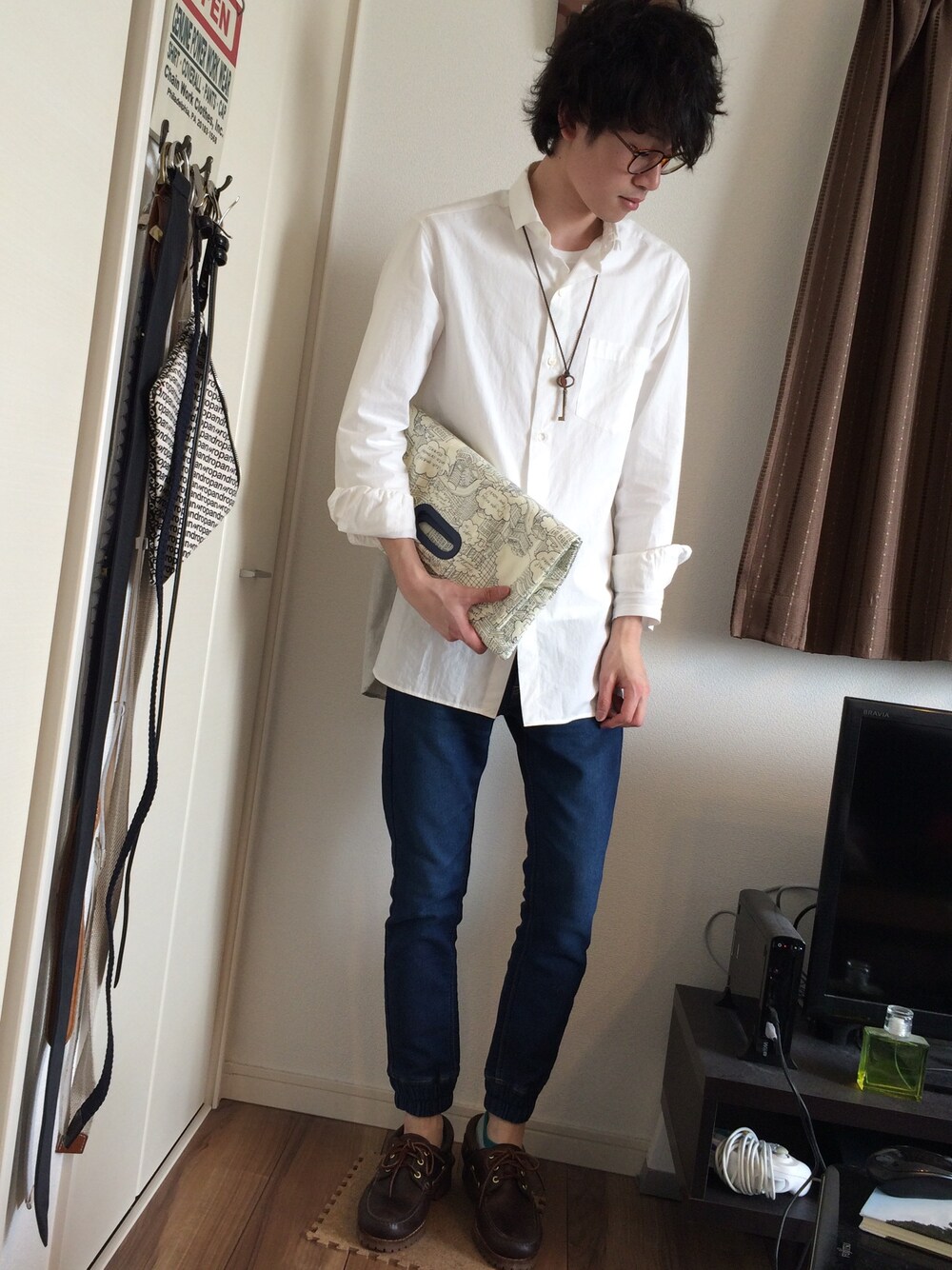 ブルー系のデニムパンツ、ベージュ系のクラッチバッグ、ホワイト系のシャツ/ブラウスを着用したメンズの春コーディネートの1枚目の写真