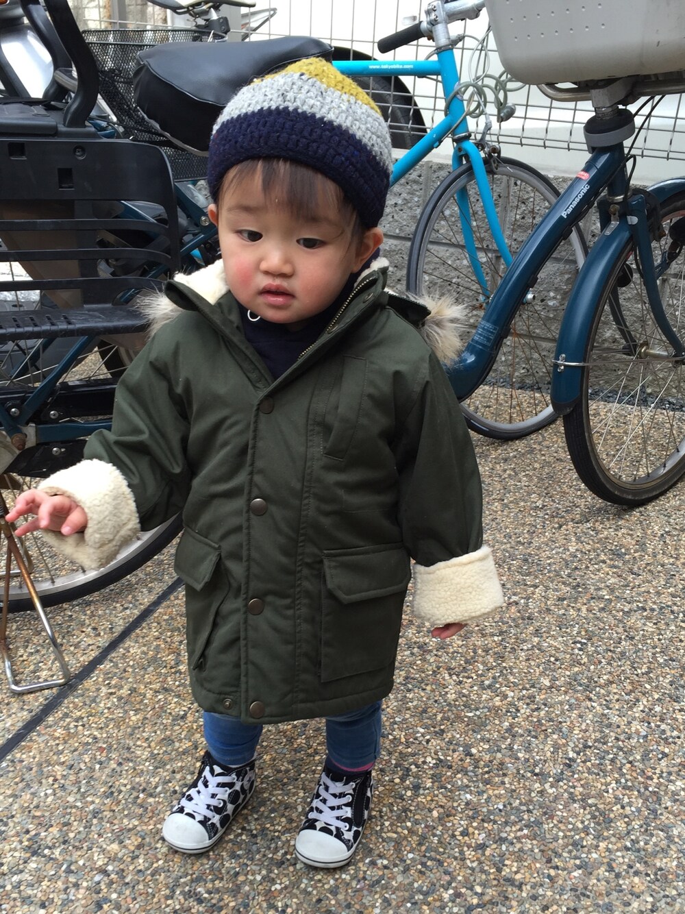 グリーン系のその他アウター、ブルー系のデニムパンツ、ホワイト系のスニーカーを着用したキッズの冬コーディネートの1枚目の写真