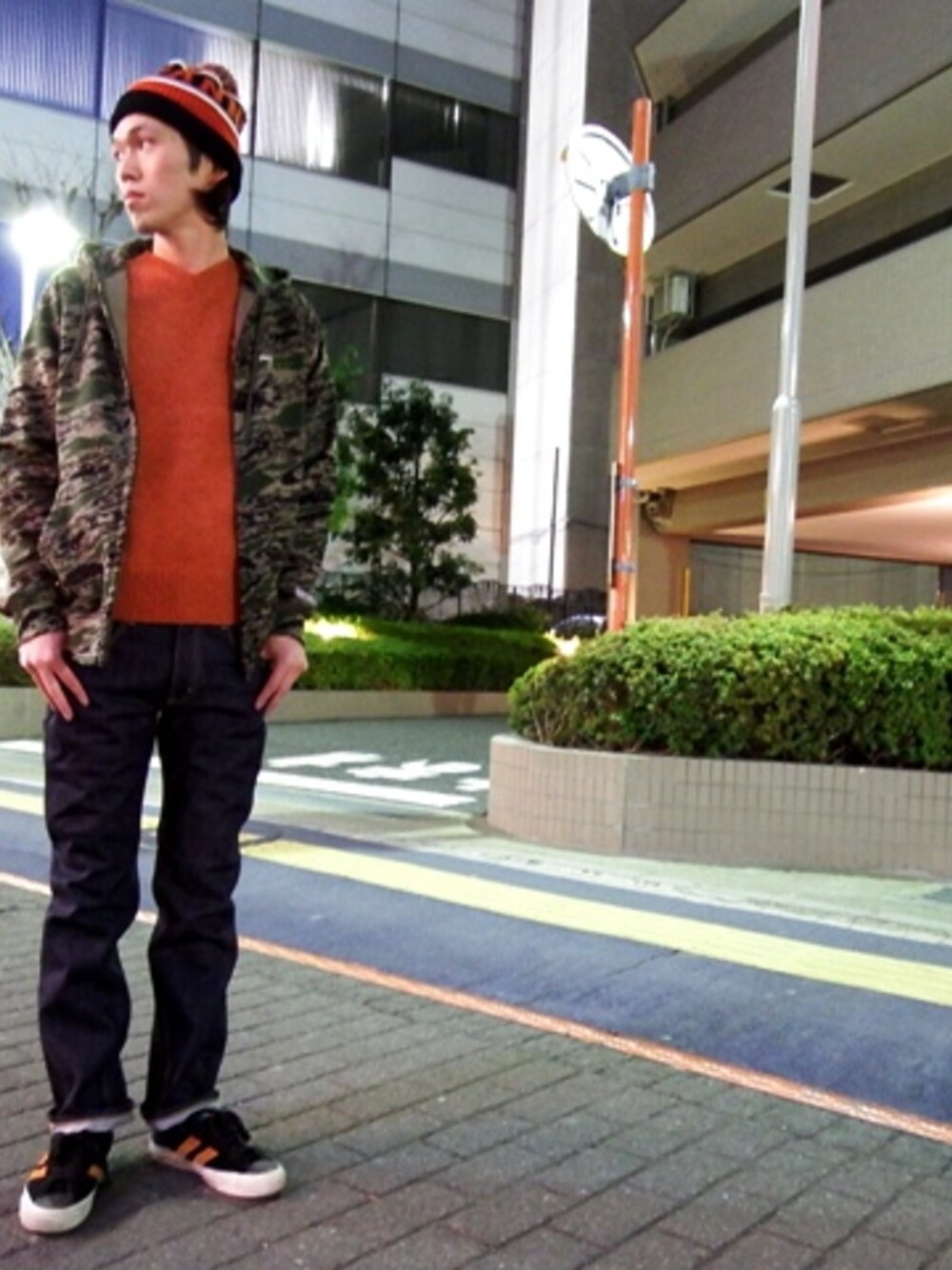 ブルー系のデニムパンツ、オレンジ系のニット/セーター、グリーン系のパーカーを着用したメンズの冬コーディネートの1枚目の写真