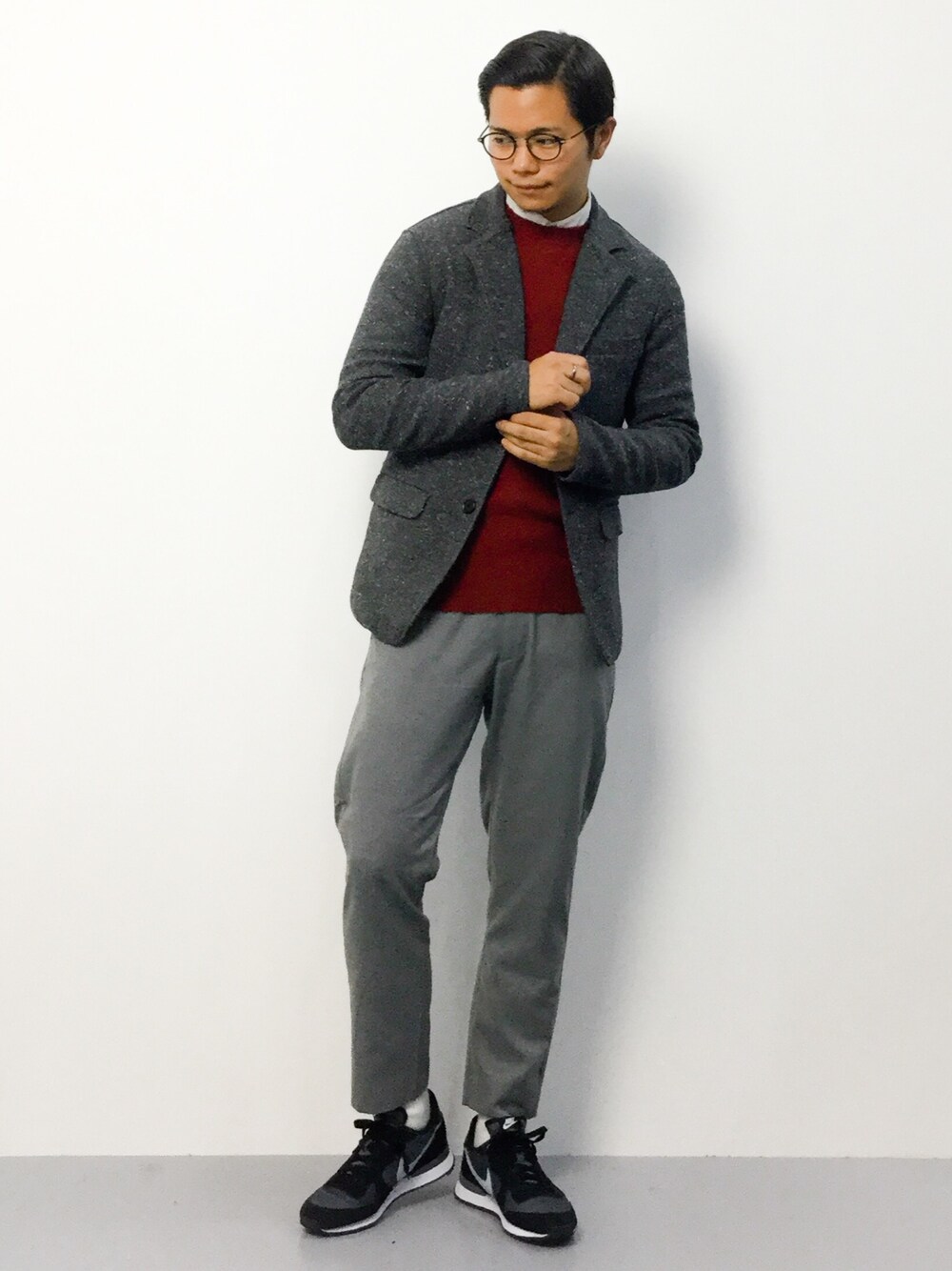 オレンジ系のニット/セーター、グレー系のスラックス、グレー系のスニーカーを着用したメンズの秋コーディネートの1枚目の写真