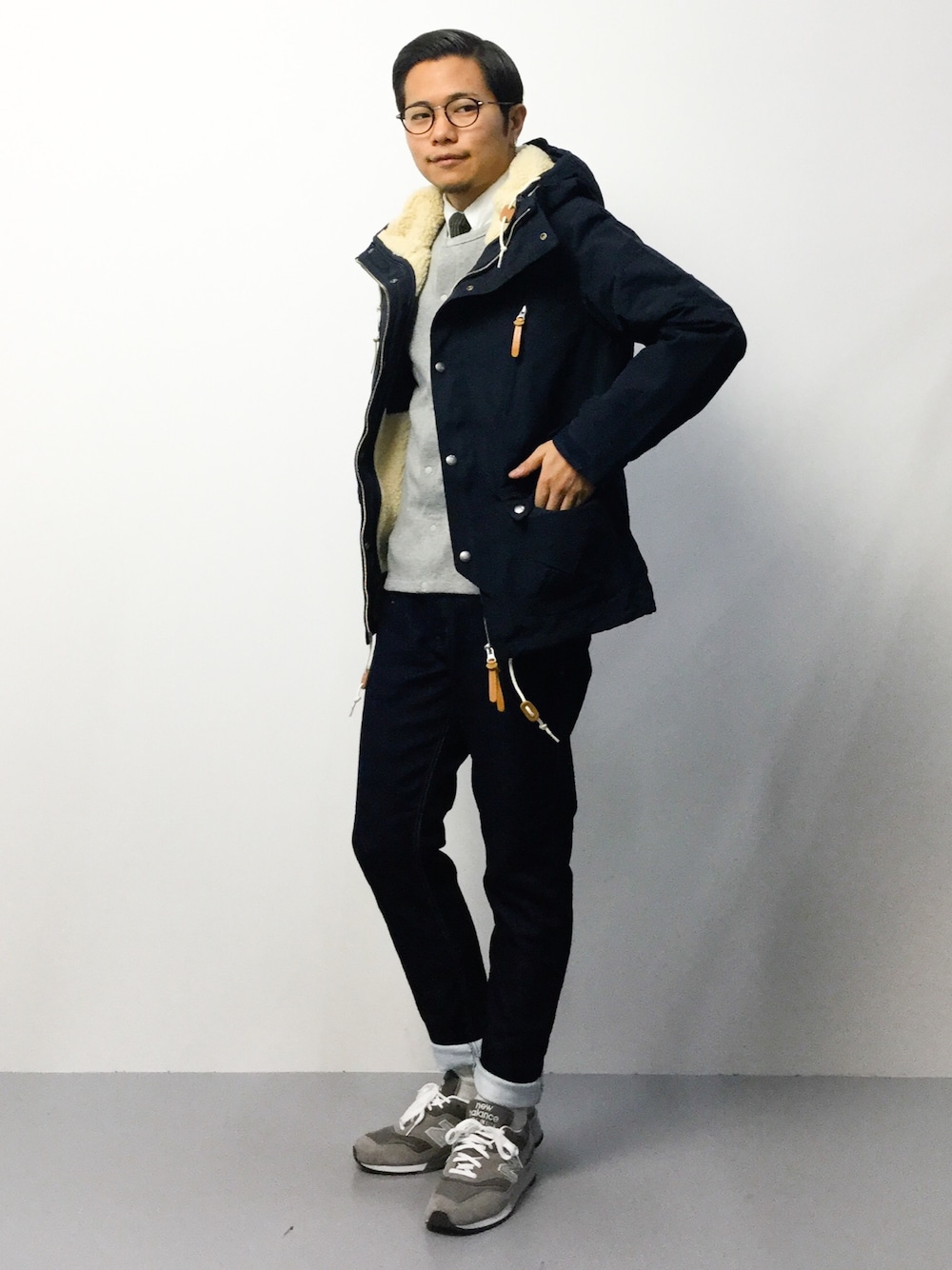 グレー系のカーディガン/ボレロ、ブルー系のマウンテンパーカー、ブルー系のデニムパンツを着用したメンズの秋コーディネートの1枚目の写真