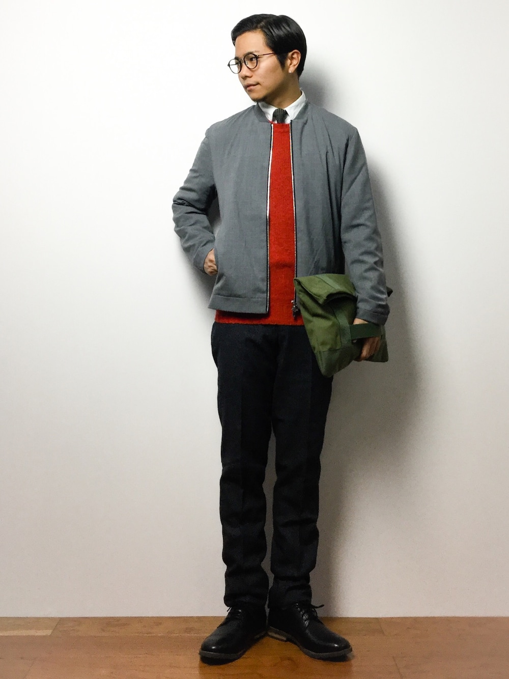 グレー系のMA-1、オレンジ系のニット/セーター、グリーン系のクラッチバッグを着用したメンズの冬コーディネートの1枚目の写真